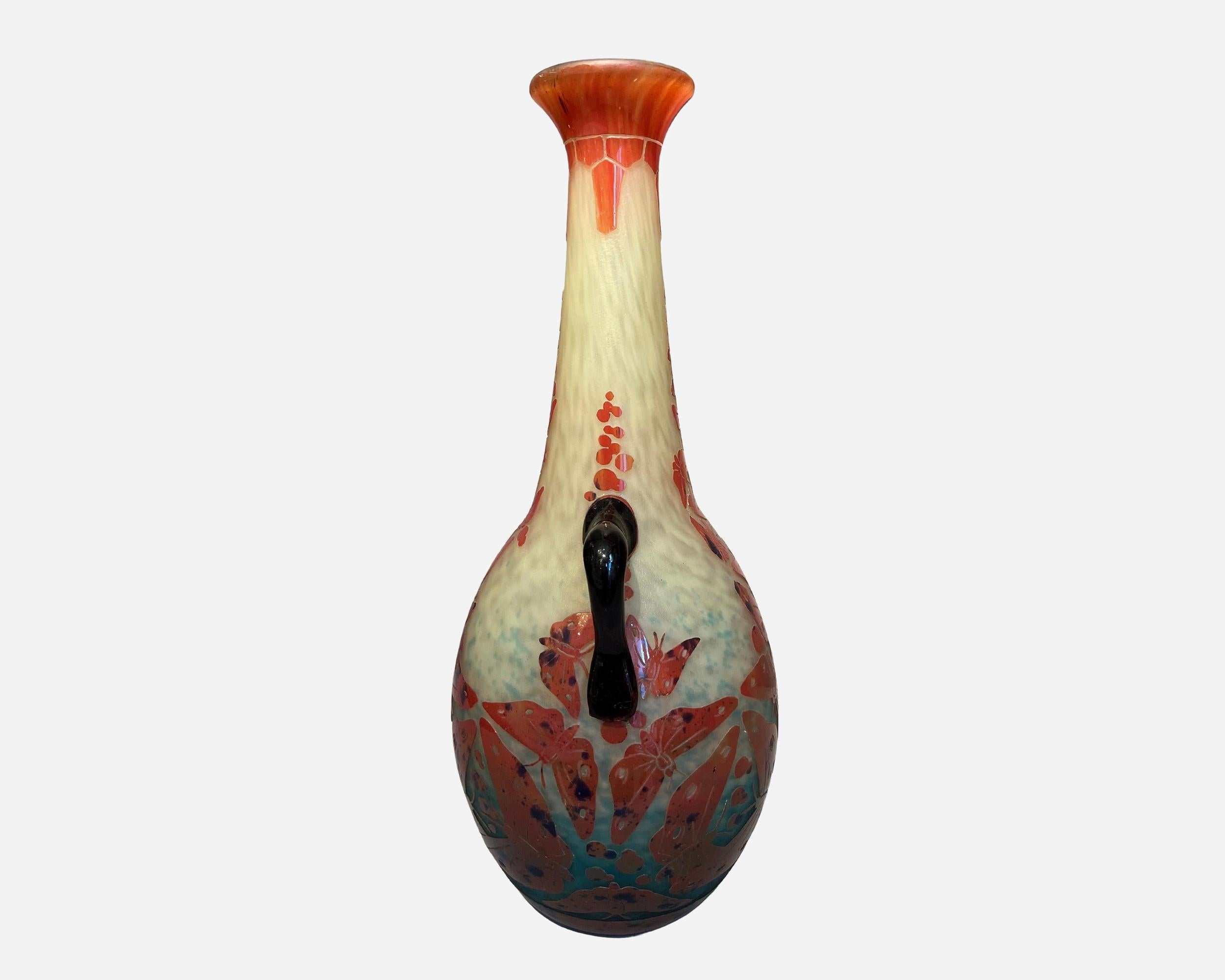 Grand vase à anses en verre multicouche gravé à l'acide, à décor de papillons tournants, rouges et mouchetés de bleu marine sur fond marmoréen jaune et bleu ciel.
Signé 