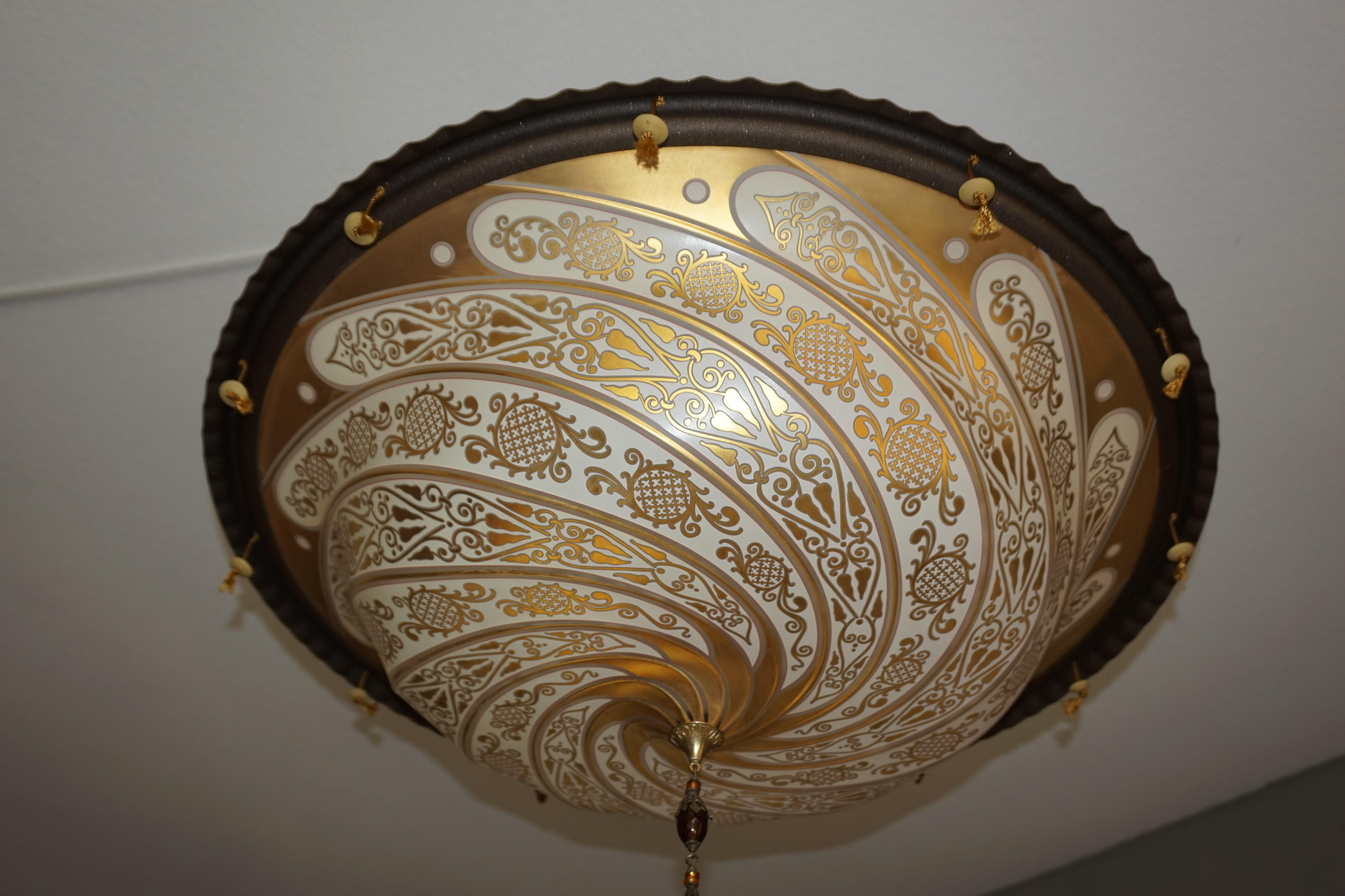 Stunning flush mount with swirling gilt motifs.

There is something Bohemian about this handcrafted, Italian pendant with its amazing pattern of flowing motifs. It is much better to see in real life, but there also is depth in the scrolling of