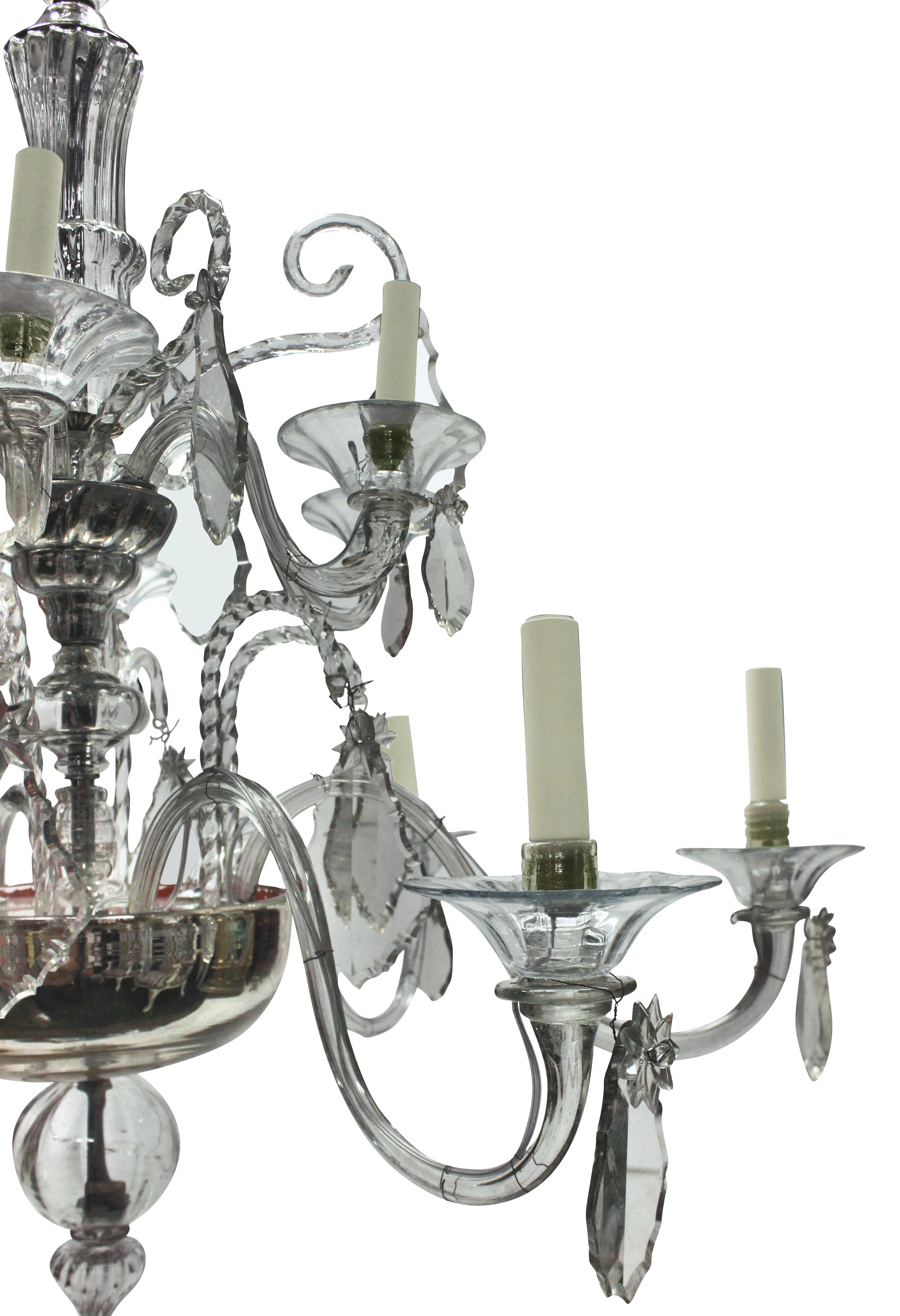 A large Venetian twelve branch chandelier of good quality in cut and moulded glass. With twelve deeply scrolled arms over two tiers, with a central bulbous stem, silvered receiver dishes, glass scrolls and pendant drops.
