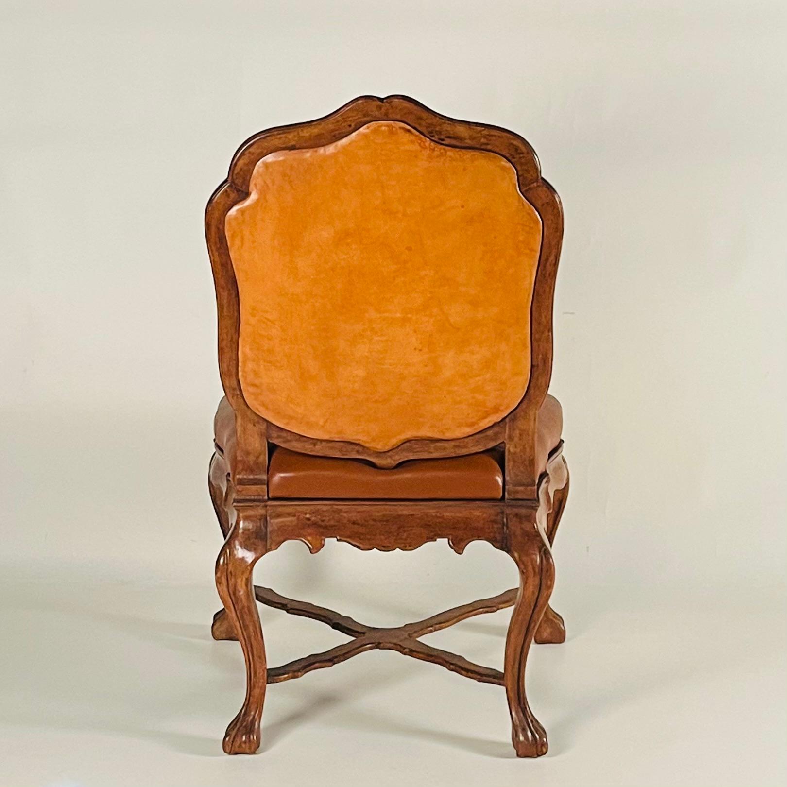 An elegant side chair that boasts impressive proportions and exquisite craftsmanship. It features beautiful carving on its walnut frame and is upholstered in fine leather. This side chair would make a sophisticated addition to a living room or