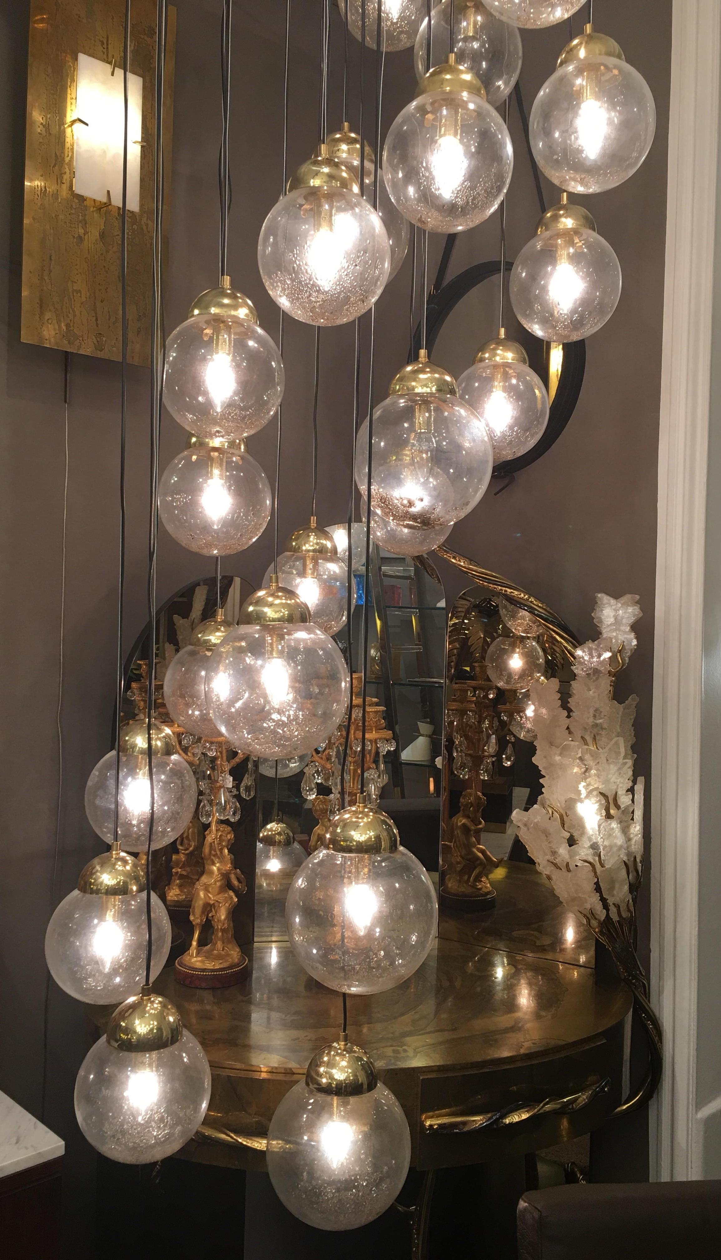 Large Murano suspension, consisting of 24 globes in blown transparent glass with inclusions of amber / gold glass in the lower part of the globes, suspended from a polished brass ceiling with steel wires and electric cables. Some globes extra, in