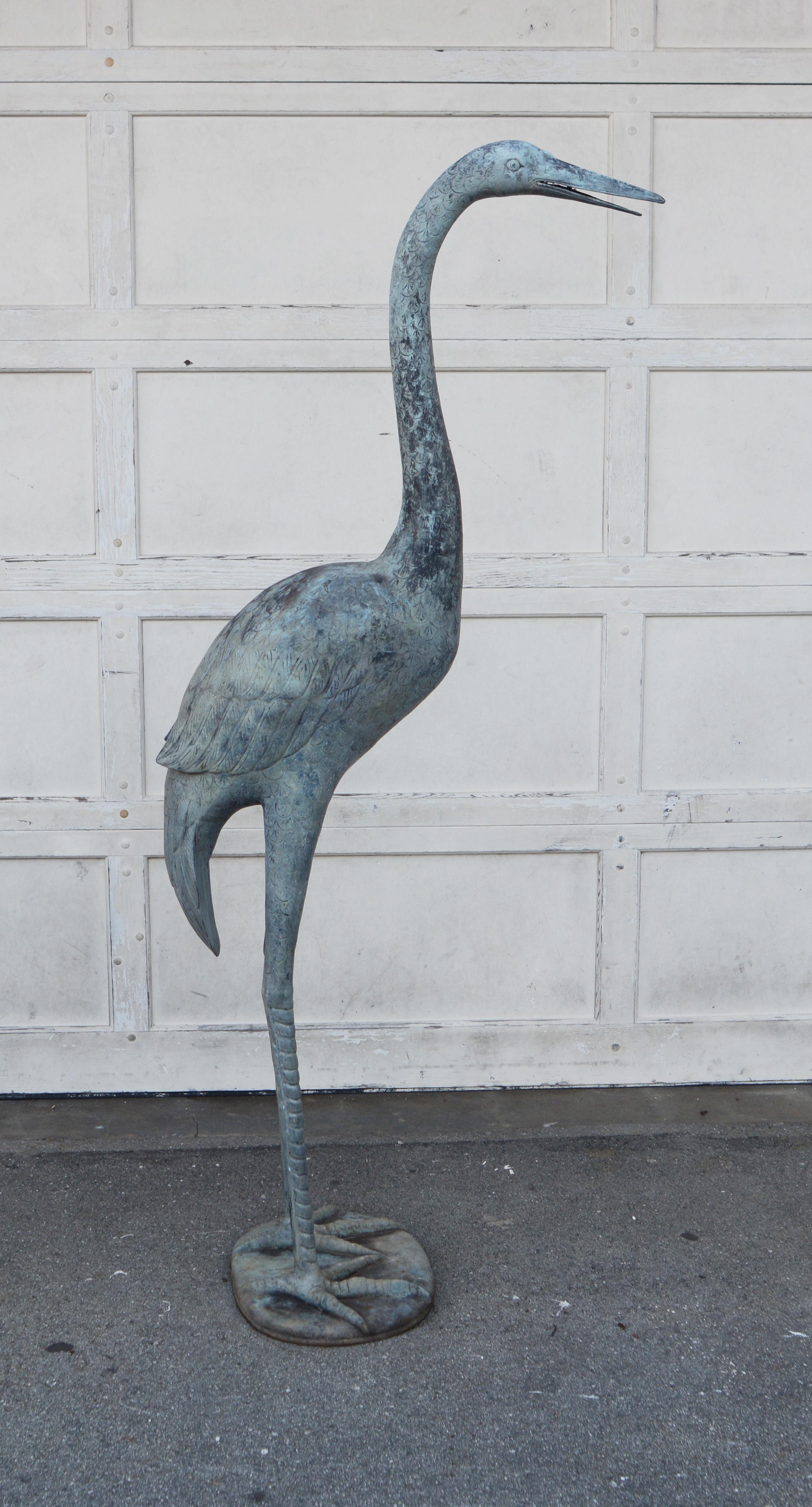 Vintage large size bronze crane. This crane has been outdoors but could be used inside as well. The verdigris patina shows some wear and discoloration. There are a few spots of deck stain on it.