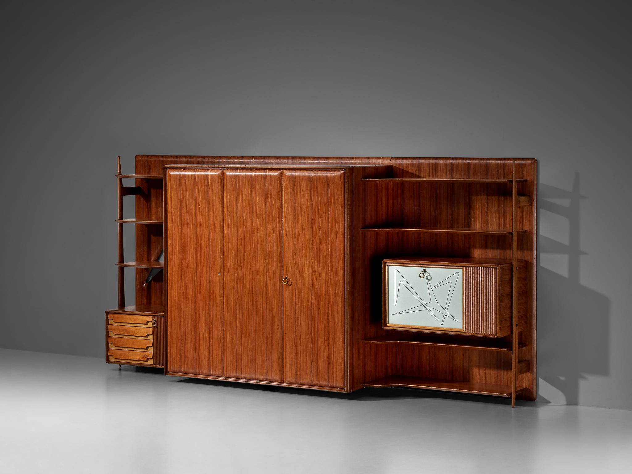 Wall unit, teak, maple, lacquered wood, brass, glass, Italy, 1950s.

This Mid-Century Italian wall unit seamlessly integrates form and function, captivating with its aesthetic allure and practicality. Its design presents a myriad of storage