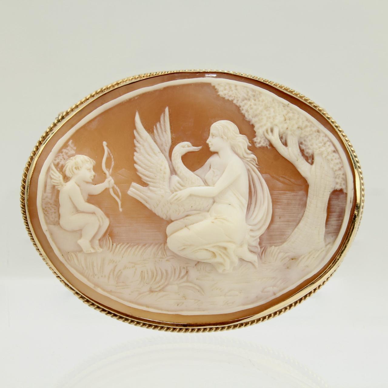 A very fine vintage carved cameo brooch.

Depicting the mythological scene of Leda & the Swan.

Carved with a scene of a swan, Leda, and Cupid by a tree. Bezel set in 14k gold.

Simply a wonderful, large scale cameo!

Date:
20th Century

Overall
