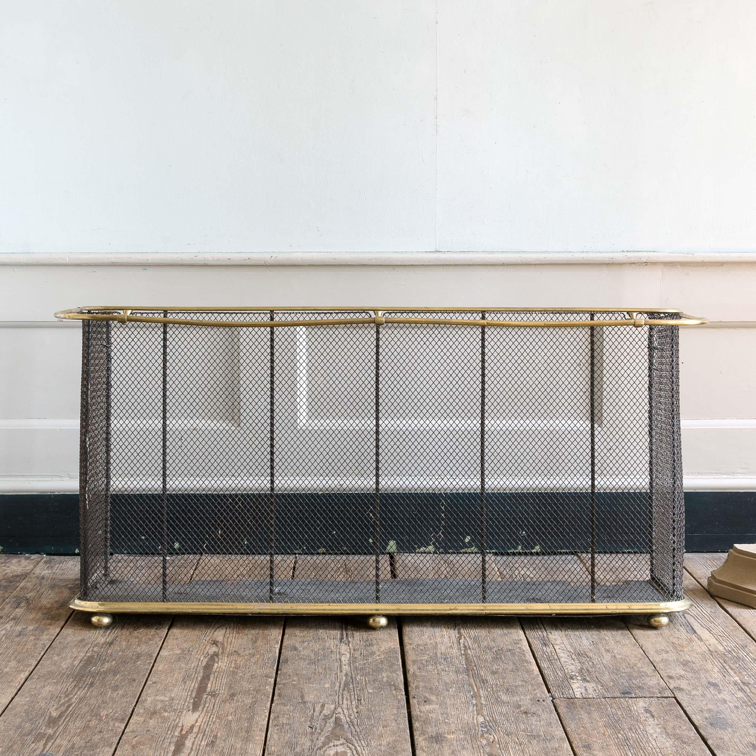 A large late nineteenth century Victorian brass nursery fender, with drying rail to the front, raised on bun feet, with woven steel mesh to the body.