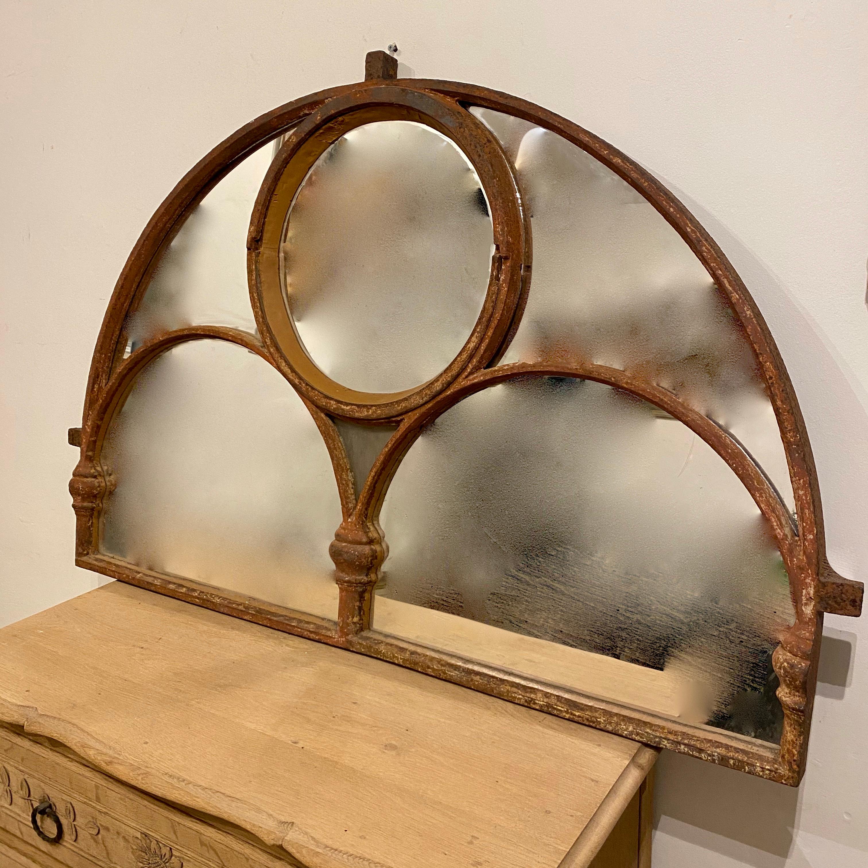 A handsome and large Victorian cast iron arched window mirror. Originally a reclaimed cast iron window from the old Brighton Aquarium and now repurposed as a mirror. The larger cast iron arch being split by two smaller inner arches with upper