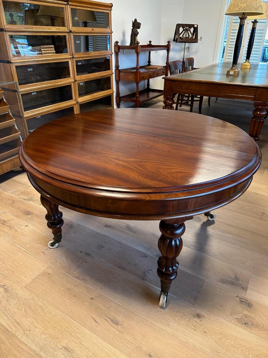 Impressive antique mahogany dining table with 4 original  leaves, allowing you to set up the table in 5 different lengths. Spacious 12 to 14 person table. The table is in perfect condition. Beautiful warm mahogany color. The extra leaves are