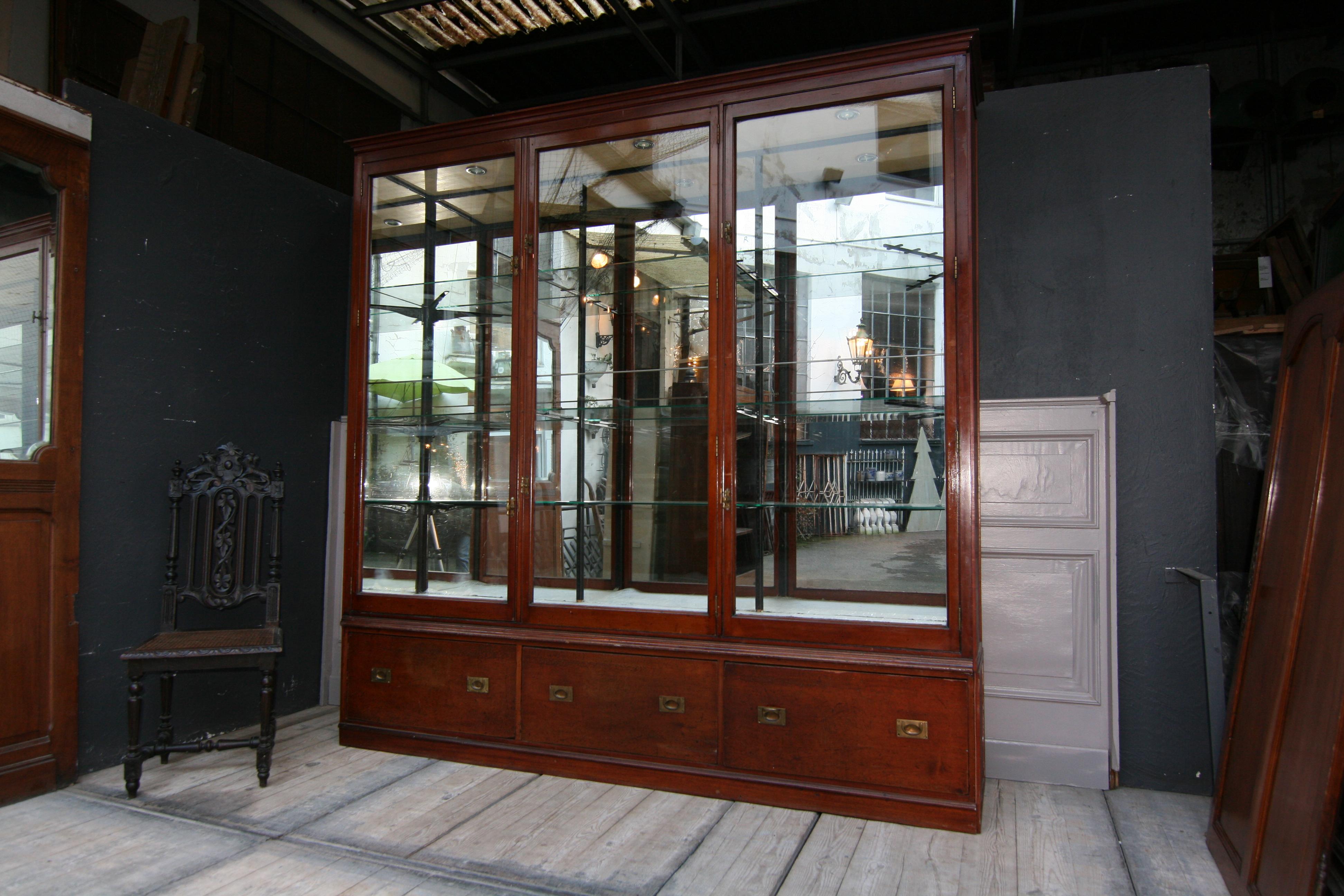 A large high quality English mahogany Victorian style display cabinet, from circa 1900.
The display cabinet consists of 2 parts. The base part features 3 large, finely mortised drawers with the typical brass handles. 
The vitrine top features 3