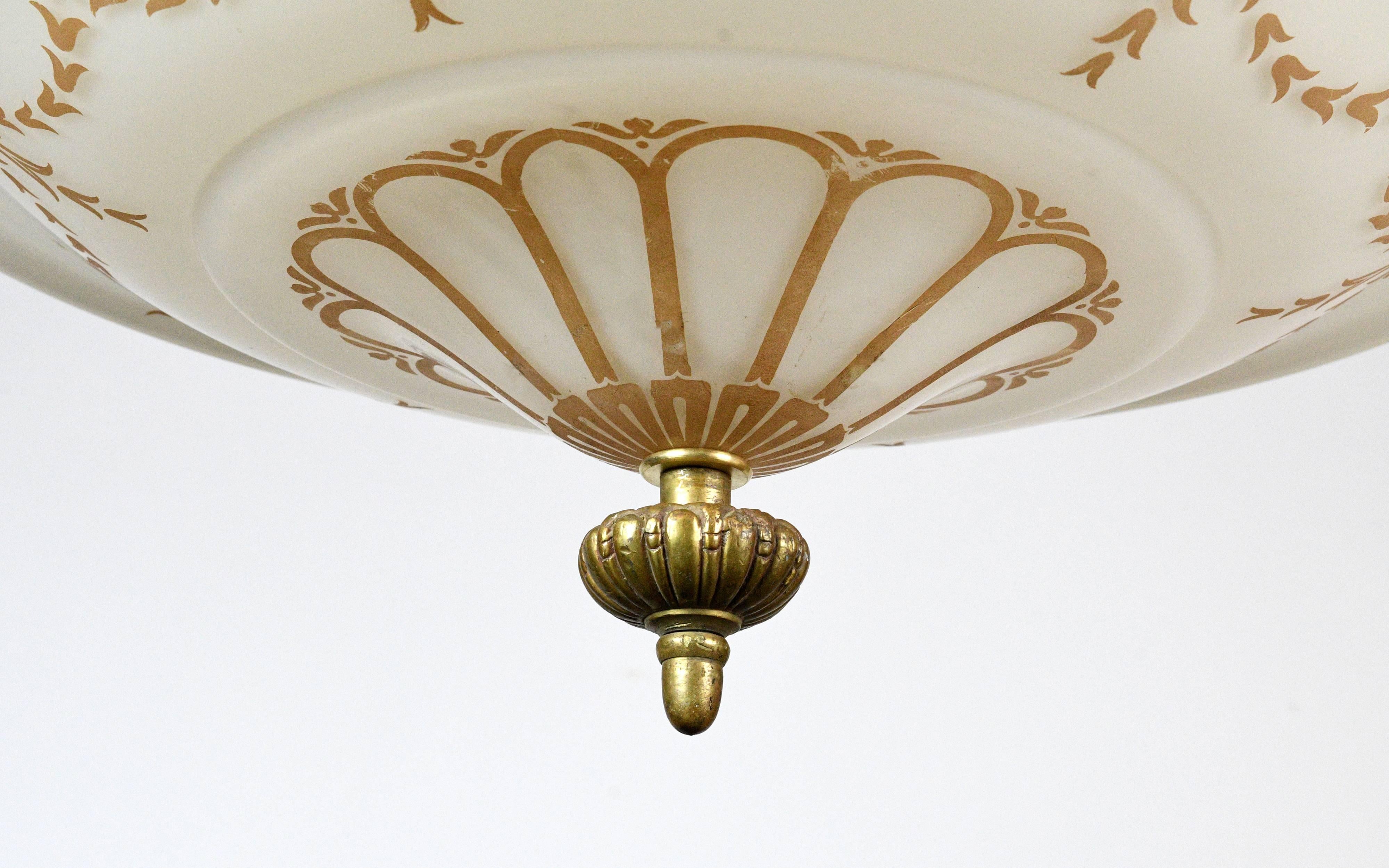 This is Victorian style at its finest. On the surface of the off-white glass shade, a pattern of repeating floral and organic shaped patterns are etched. The shiny gold-colored fitter is highly decorative, and the acanthus leaves are an added bonus,