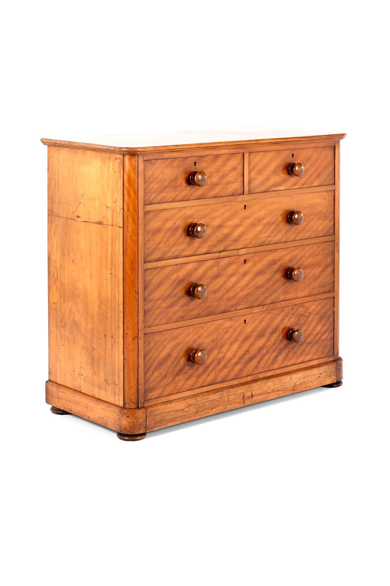 A well-proportioned Victorian satin birch chest of drawers with an arrangement of two short over three long drawers.

The drawers have the original bun handles, brass locks and escutcheons,all raised on a plinth base with diminutive flat bun