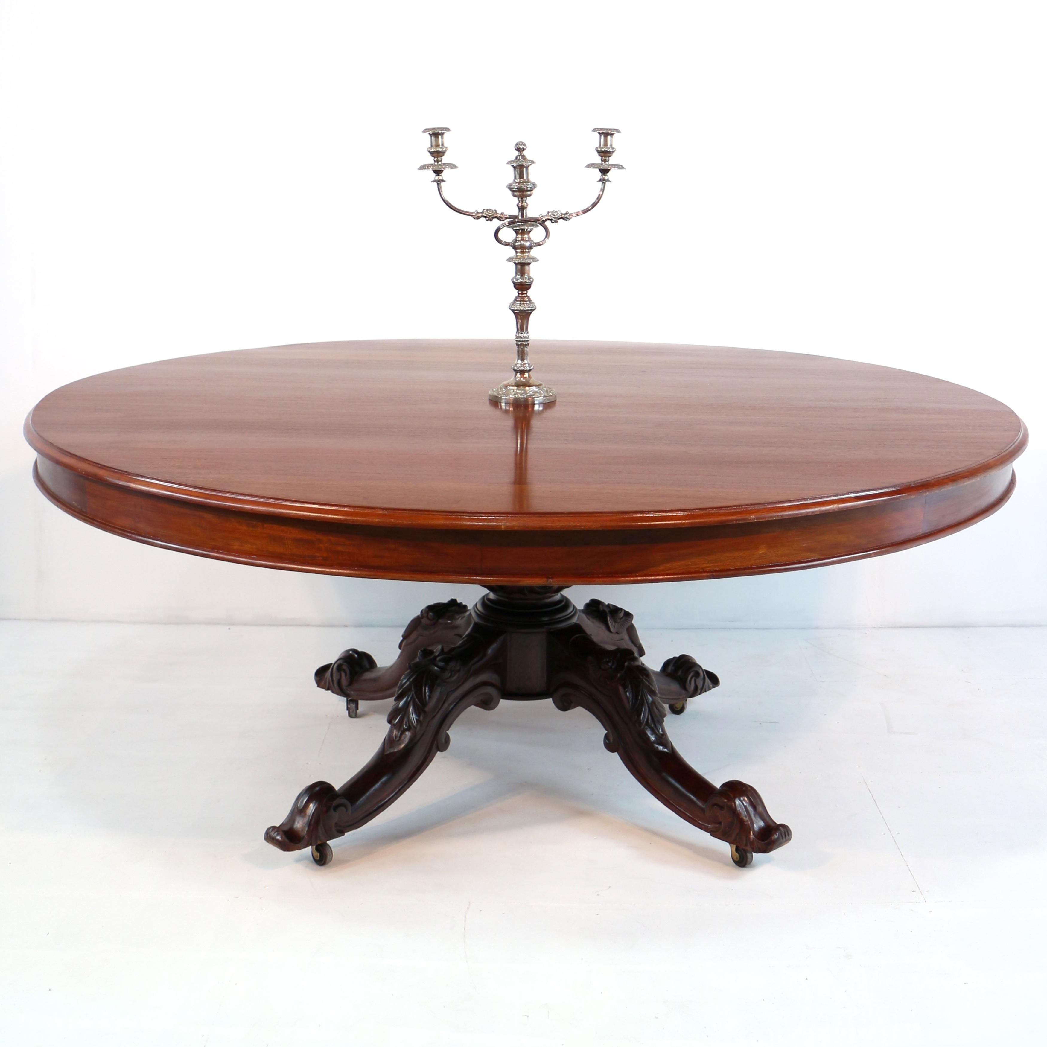 A large 6ft 7in / 2m diameter Victorian style solid mahogany centre, the circular top with a moulded edge and frieze and raised on an acanthus carved column with four downswept legs carved with C-scrolls, fruits and flowers and with scroll toes,