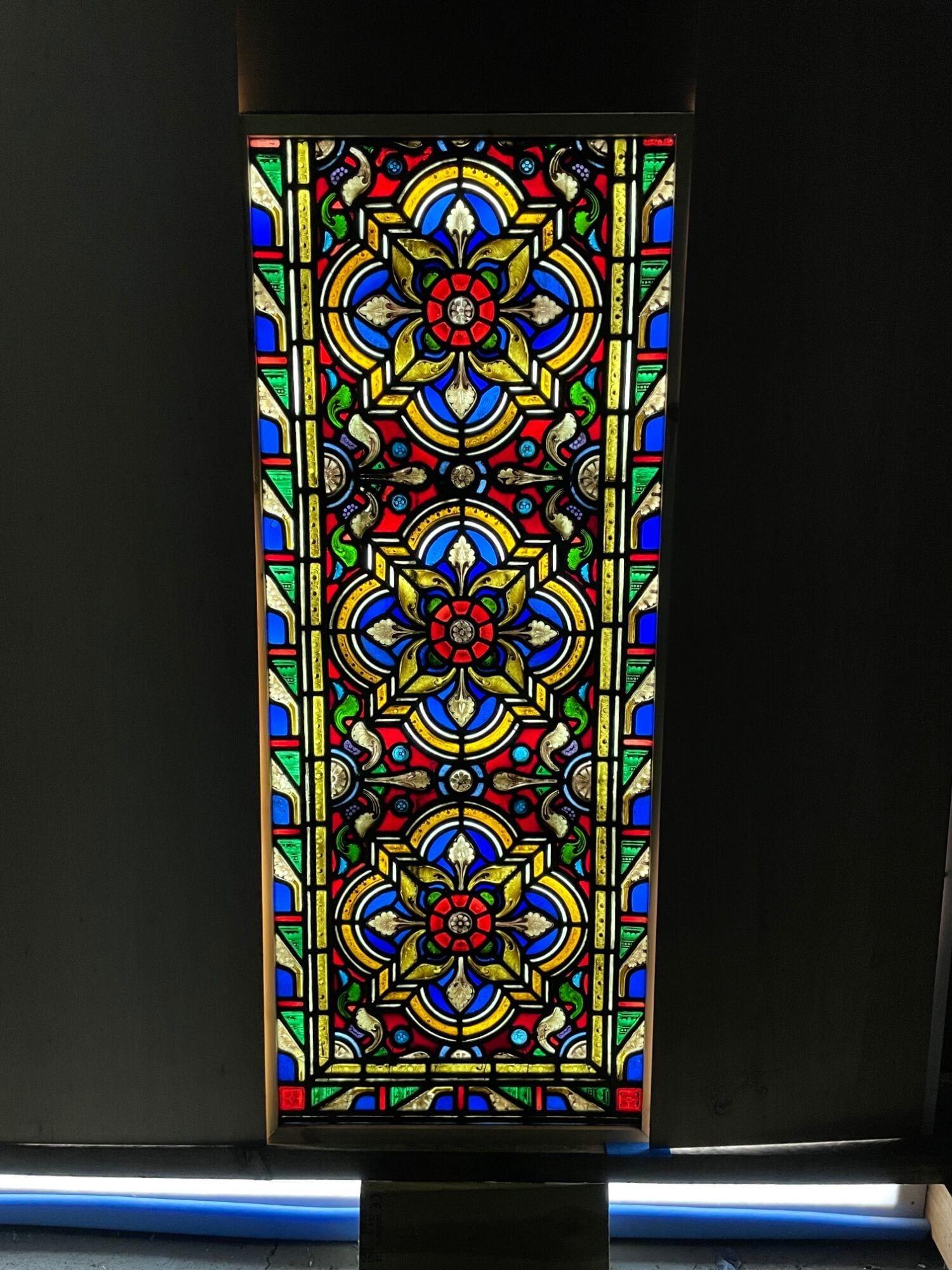A large antique Victorian late 19th century stained glass window, originally from a church in northern England. Three hand painted detailed flowers, thought to be a stylised Tudor Rose design, sit at the heart of this piece. It incorporates both