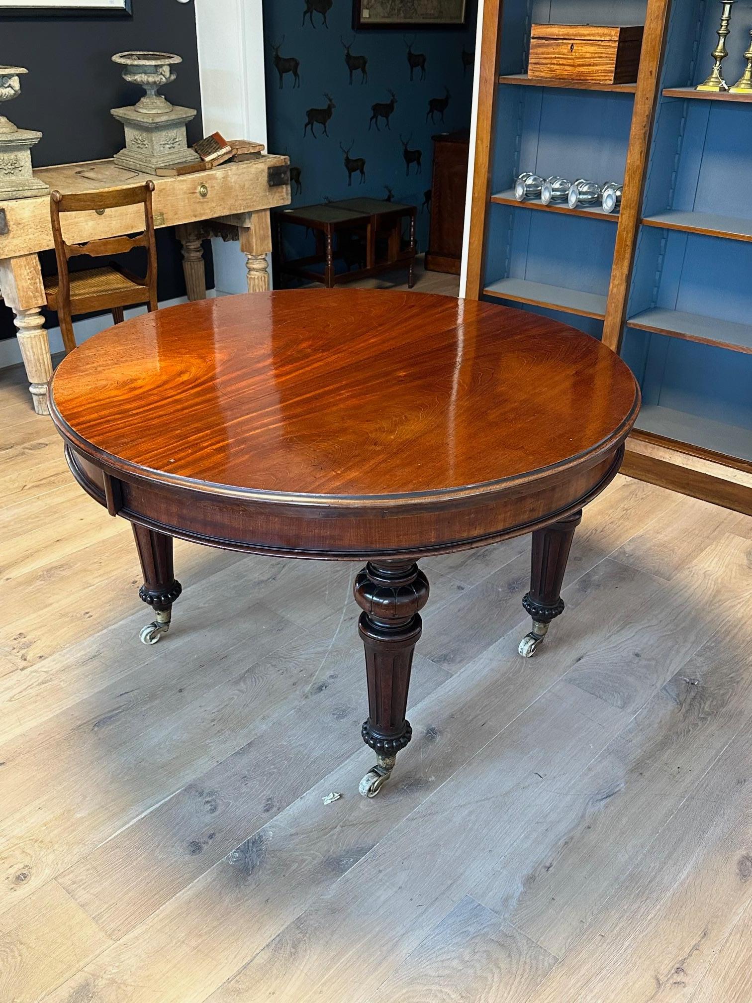 Beautiful antique walnut dining table with three additional leaves. Completely in original condition. Lovely warm color. The table can be opened with a  handle, allowing one, two, or three leaves to be added. This increases the table's diameter from