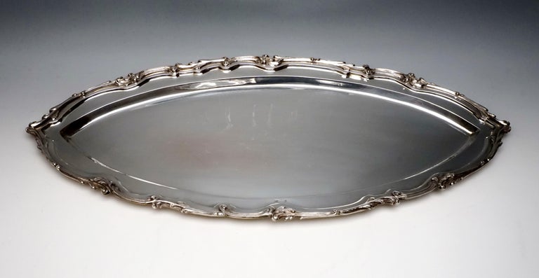 Large silver plate shaped like a boat in a smooth, simple design with a three-dimensional rocaille band on the edge of the raised, exposed rim.

Branded by the Diana's head mark, the Viennese official hallmark 1872 - 1922 for 800 silver