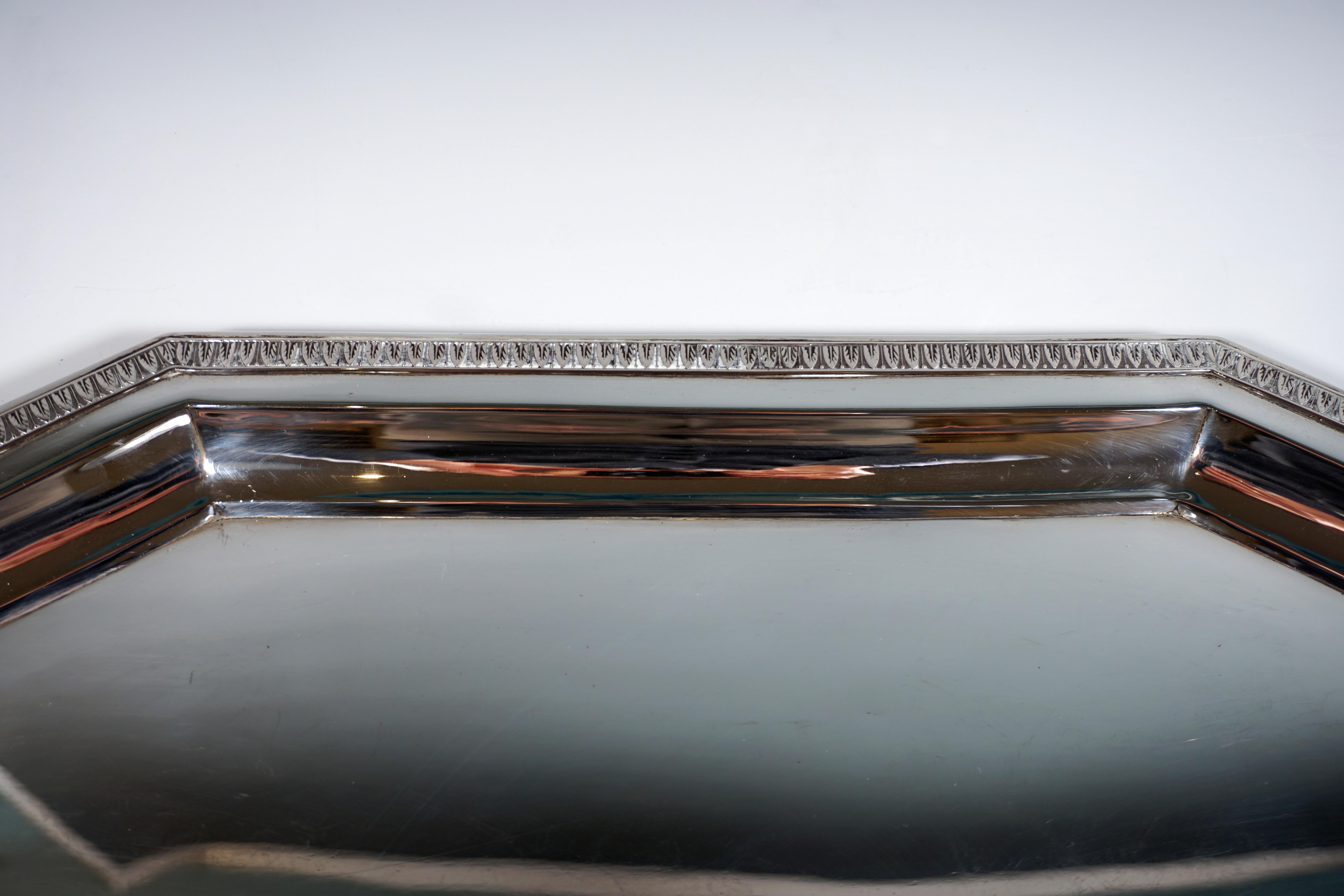 Octagonal shaped silver tray in a smooth, simple design with raised, flared edge with circumferential palmette band, extension of the edge piece on the broad sides by incised handles.

Hallmarks:
Diana's head - Viennese official hallmark 1872 -