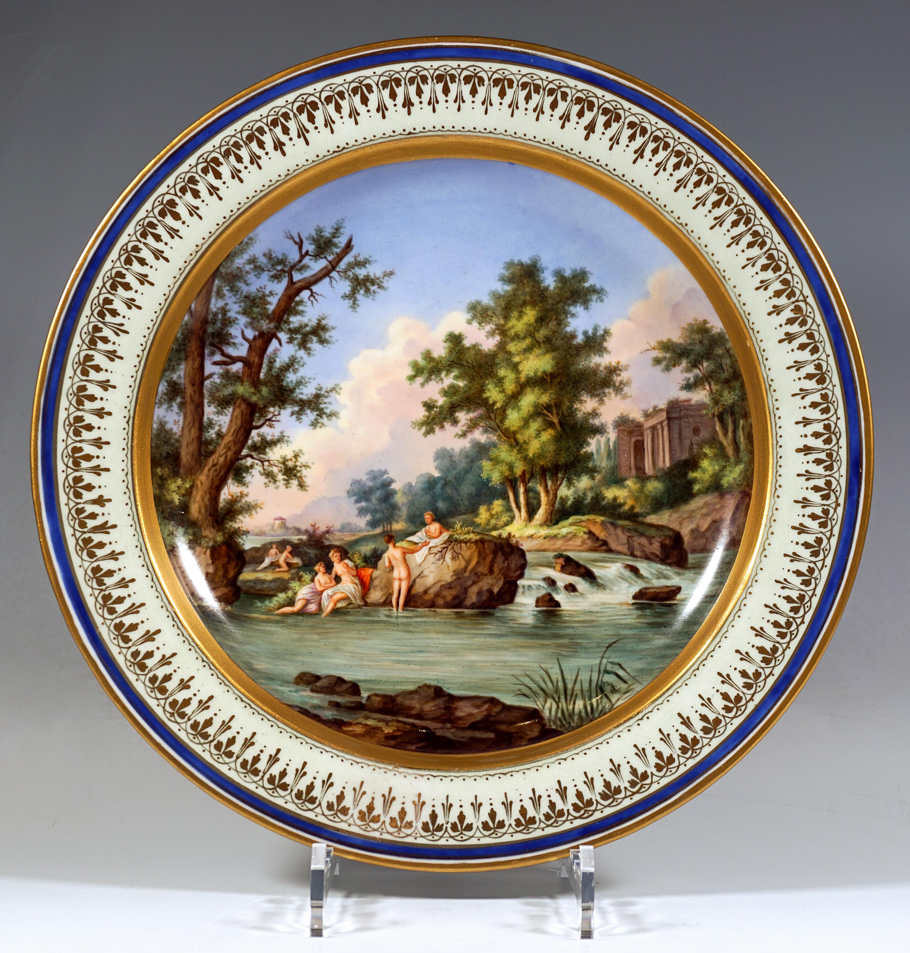 Exceptionally large porcelain plate decorated with fine polychrome painting: a romantic landscape with trees and ruins filling the entire surface of the plate, in the foreground a waterhole with a staffage of figures: naked women wrapped in cloths