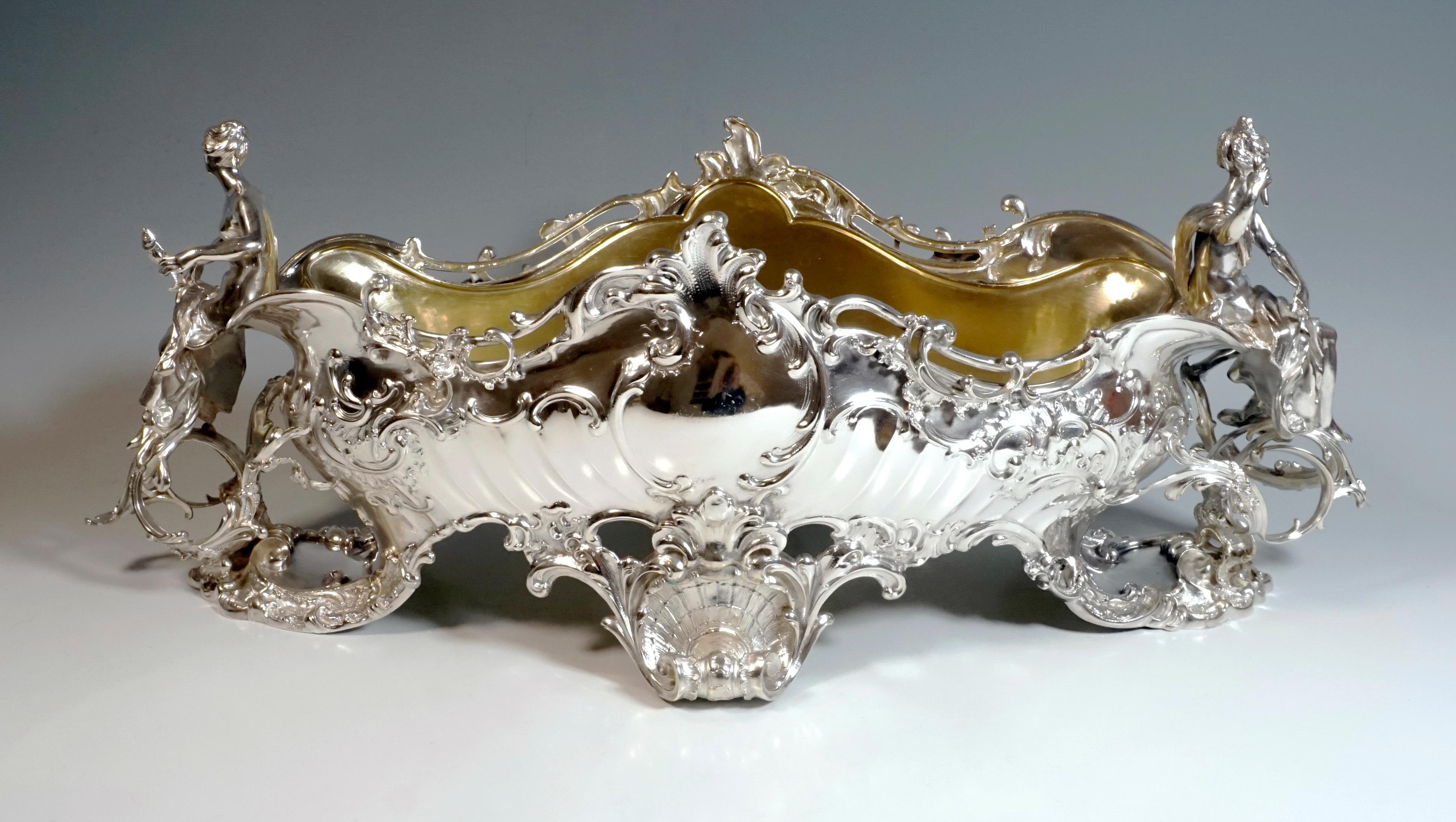 Large, elaborately designed silver centerpiece on an oval ground plan, the cambered, curved walls with ample rocaille decoration, on the long sides large cartouches in the middle over a slightly flared rocaille and volute foot with shell embossing.