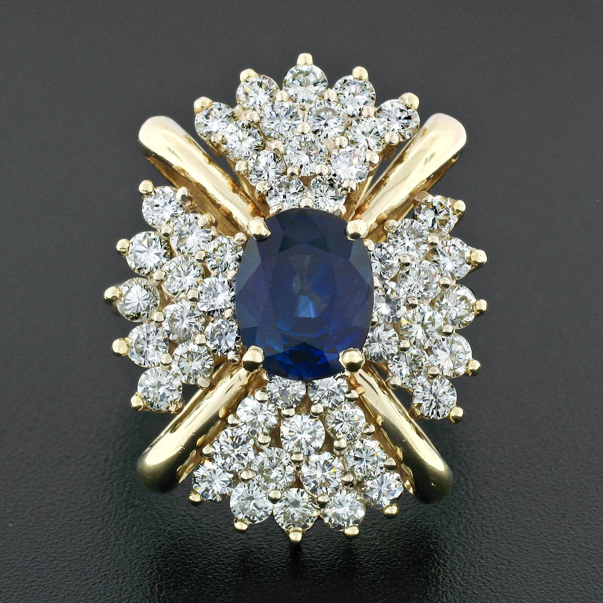 This large and spectacular sapphire and diamond statement ring was crafted from solid 14k yellow gold. The ring features an exactly 3.18 carat, GIA certified, oval cut Ceylon sapphire which is prong set at the center of its tiered oval design. The