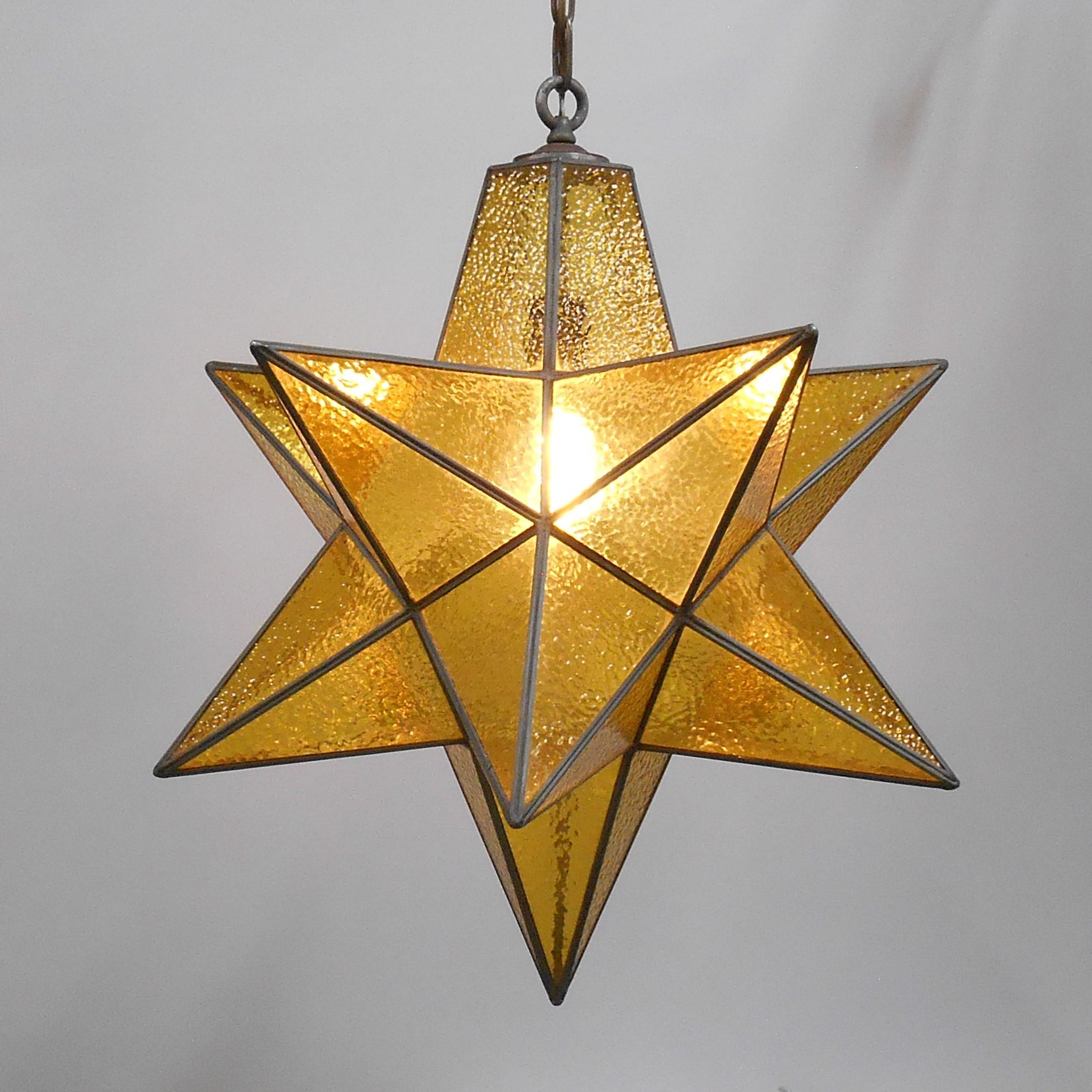 A beautiful Moravian star pendant with clear gold pebbled glass. This over scaled star has great presence. Wear consistent with age and use. There is one small crack in the glass located on a top surface on one of the top pyramidal extensions (shown