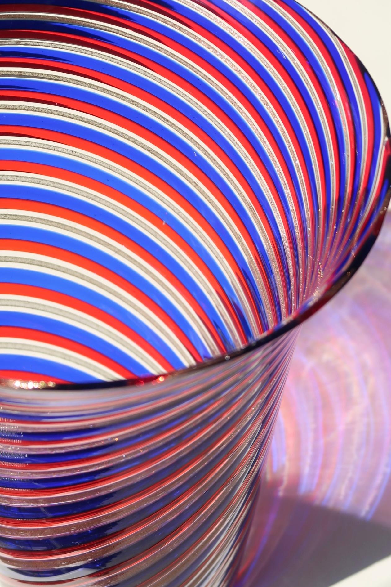Ualmindelig stor vintage Murano vase med låg i dybe nuancer af rød, blå og kobber. Mundblæst i glas i en teknik som primært er kendt fra glashusene Venini, Gio Ponti og Fratelli Toso. Håndlavet i Italien, 1970erne.
H: 26,5 cm D:20,5 cm