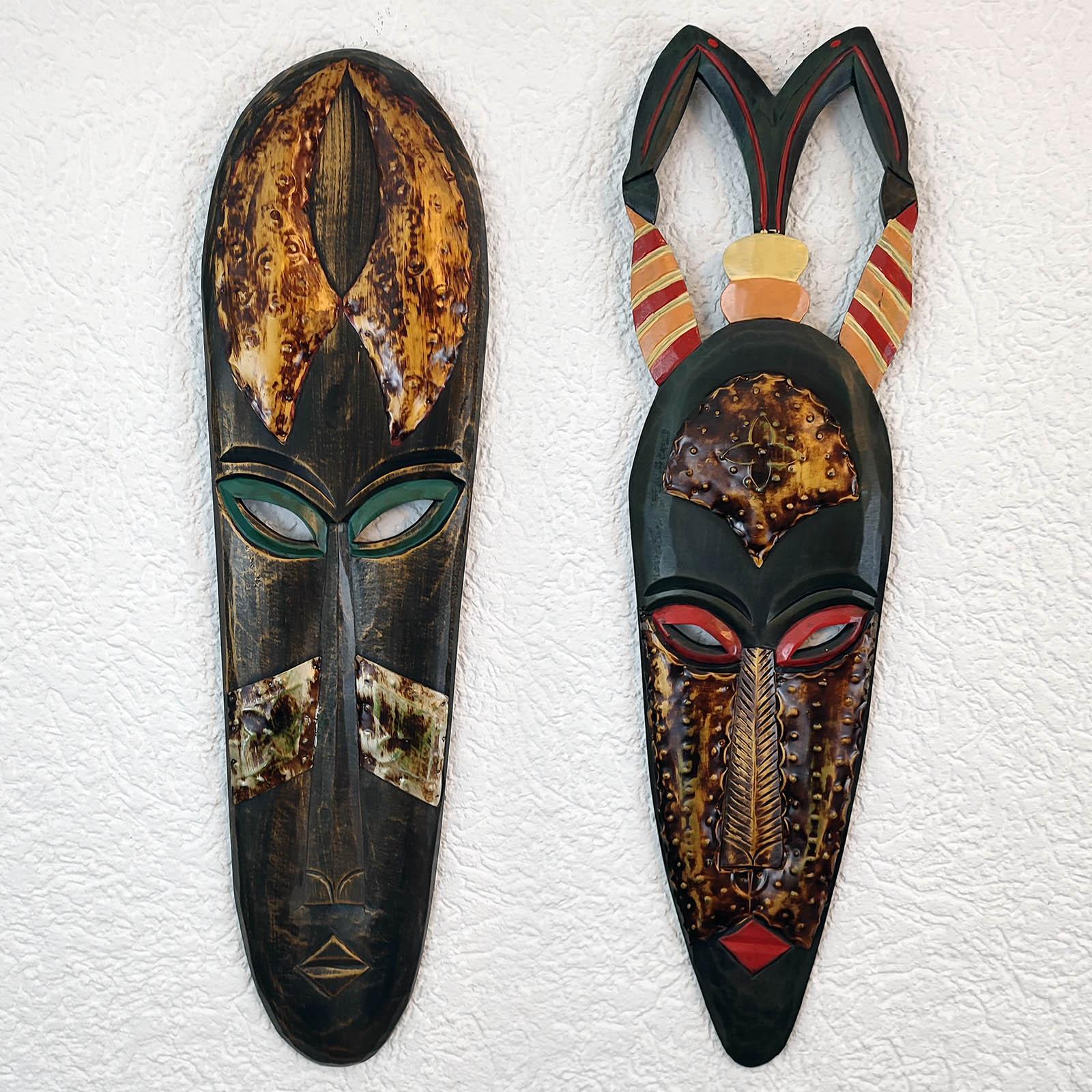 Pair of large vintage hand-carved wood African Tribal masks, richly decorated with intricate tribal motifs and metal inlays. 
Beautifully decorated, painted details and hammered metal, with hooks, ready to hang. 
Circa 80 cm high (2,6 ft)

In a