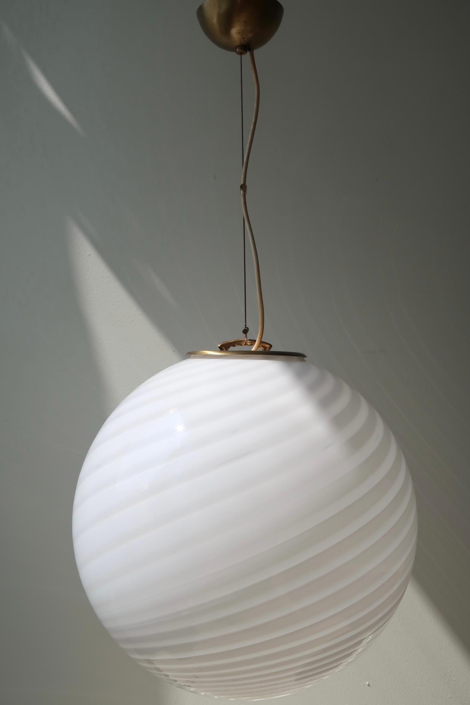 Grand plafonnier suspendu vintage de Murano en verre opalin blanc. Le verre est soufflé à la bouche et présente une forme ronde avec un magnifique motif tourbillonnant. Fabriqué à la main en Italie, dans les années 1970, et livré avec une suspension