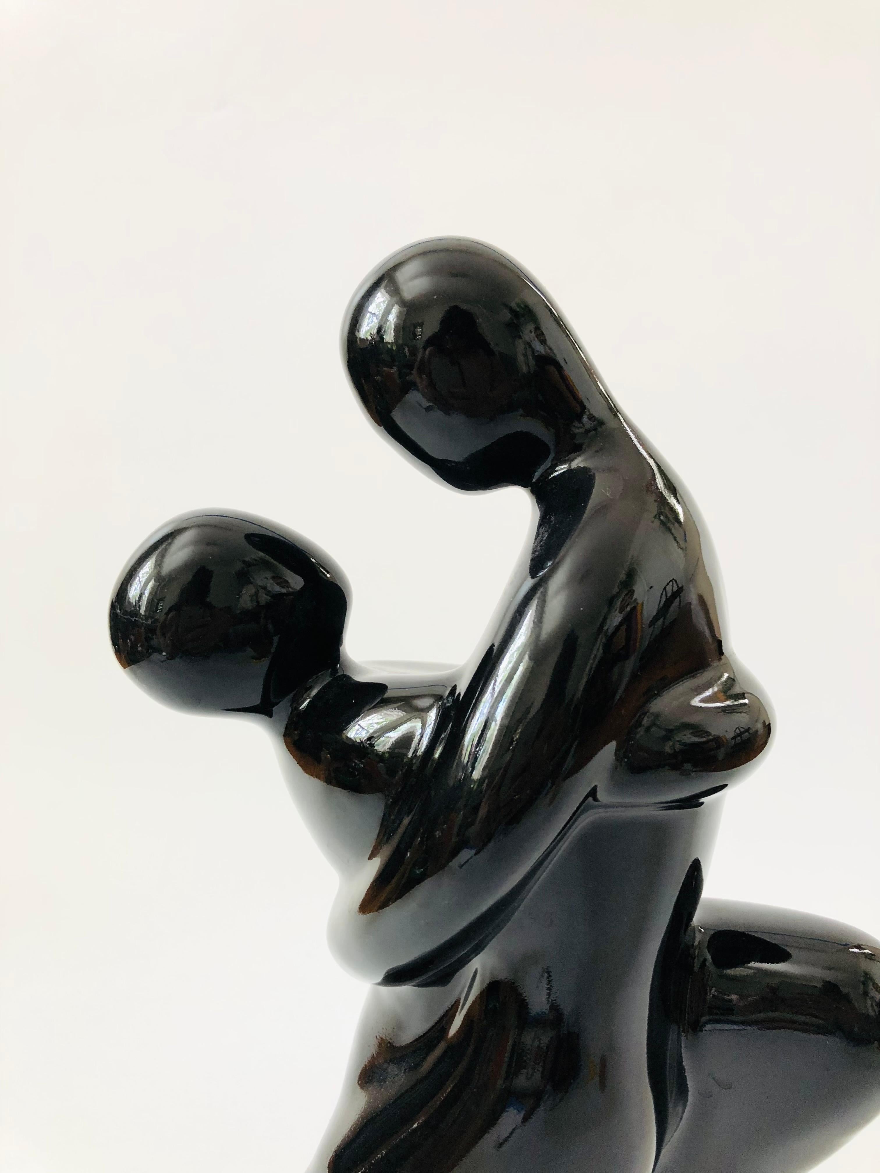 A large 1980s figurative ceramic sculpture by Haeger. Beautiful deco stylized detailing to the embracing couple, finished in a high gloss black finish. Sticker on the base by Haeger.