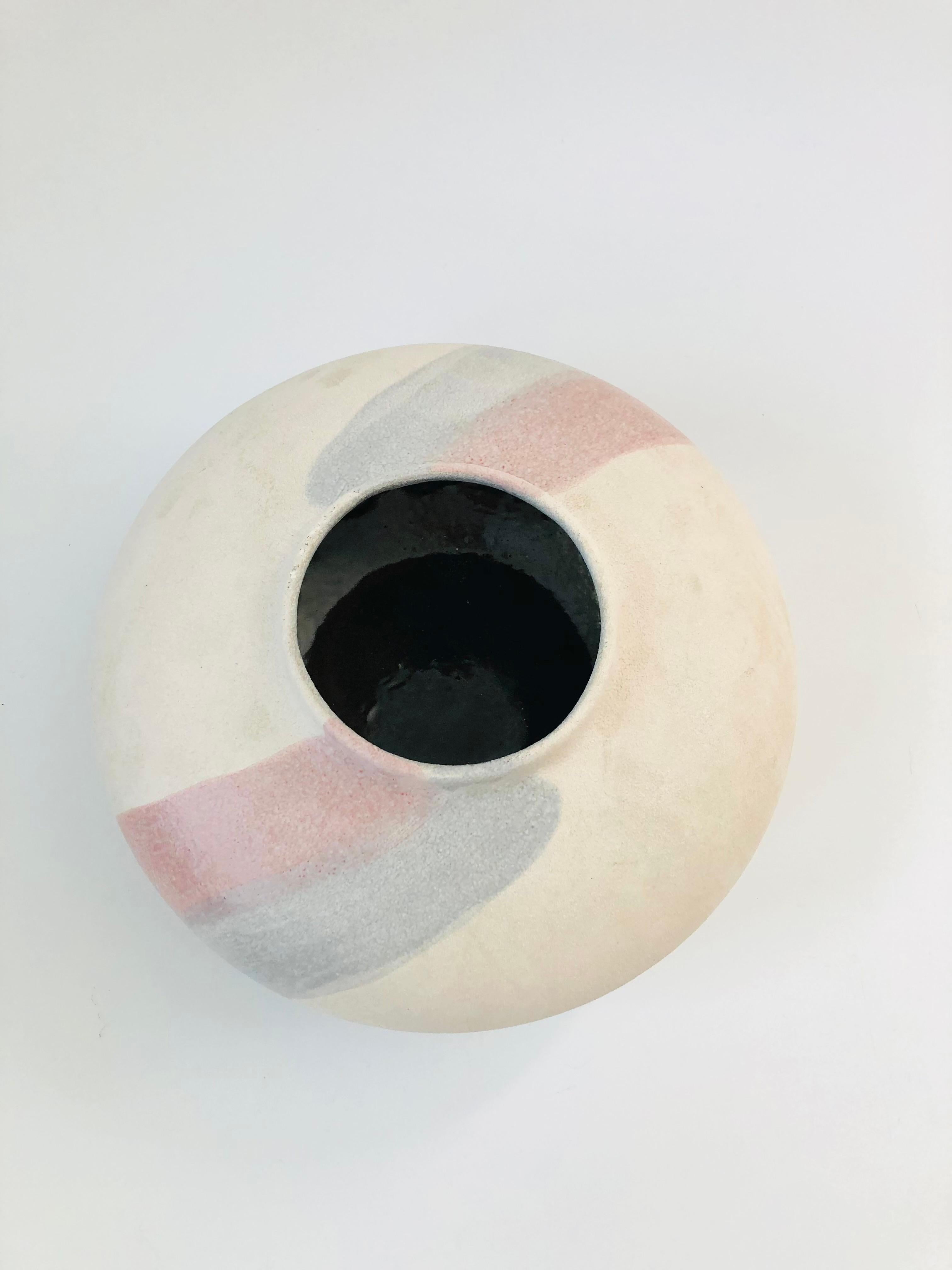 A large vintage 1980s potter vase. Nice flat circular shape with textured finish to the pottery. Two painted stripes of pink and blue decorate the surface. The interior has a glossy black finish. Perfect for creating a sculptural floral arrangement.
