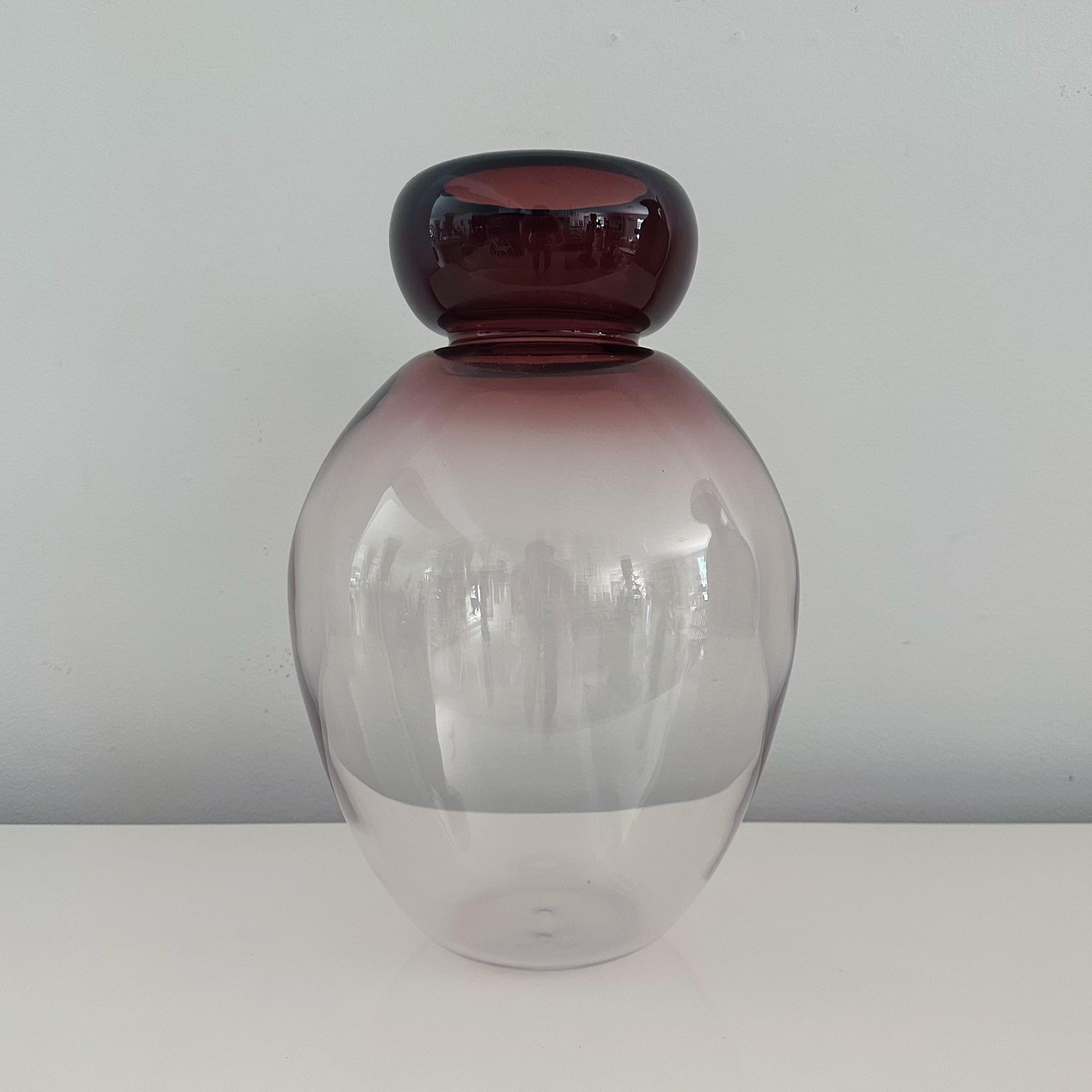 The Murano vase showcases large, bulbous shapes in captivating shades of cranberry that gradually transition into a transparent glass. Signed 