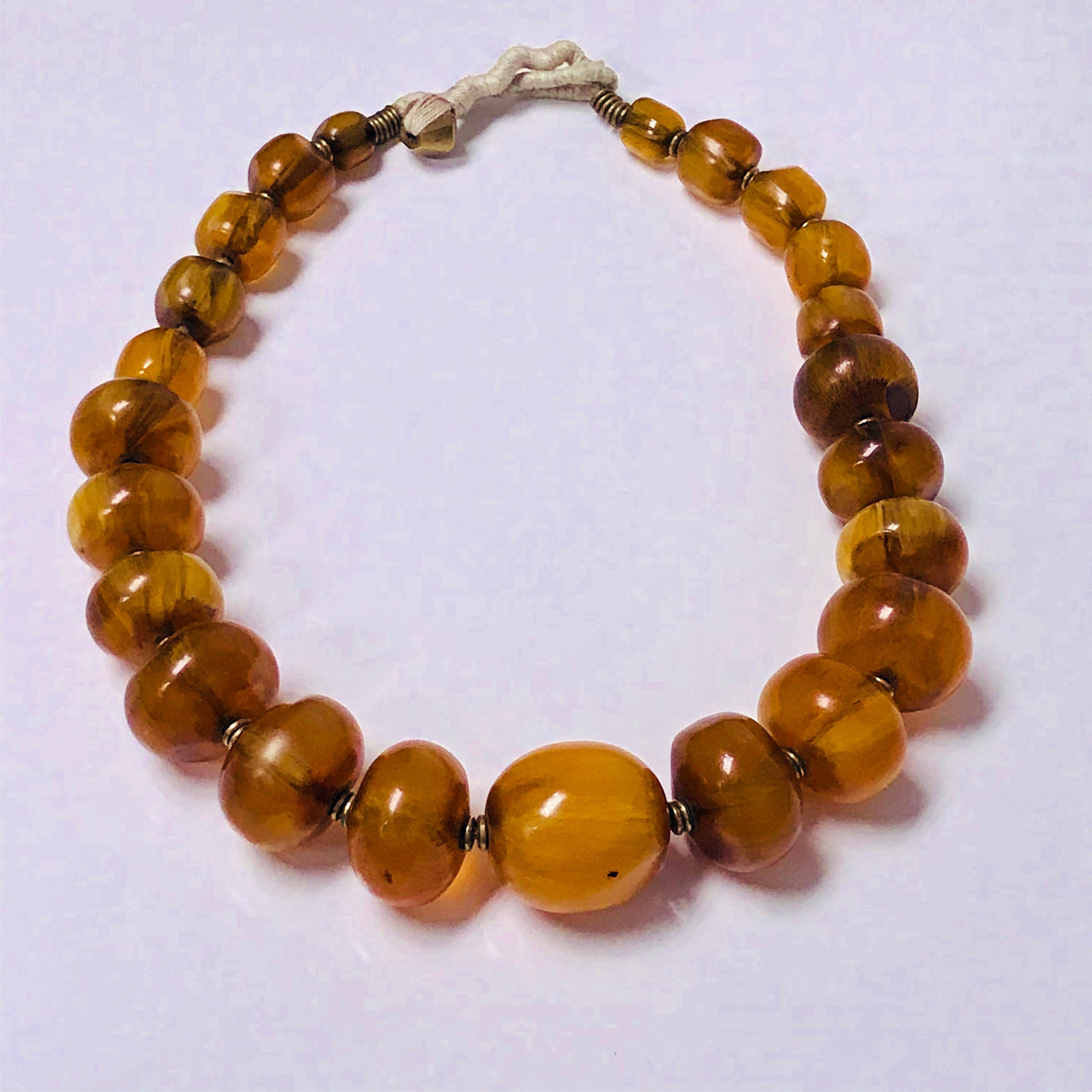 Vintage large Baltic Amber nugget beads Necklace. Semi polished and strung on rope, each bead knitted between with small brass discs. Ambers have varied inclusions, swirls of opaqueness, dark spots, dimples. Approximate length: 24 inches with rope