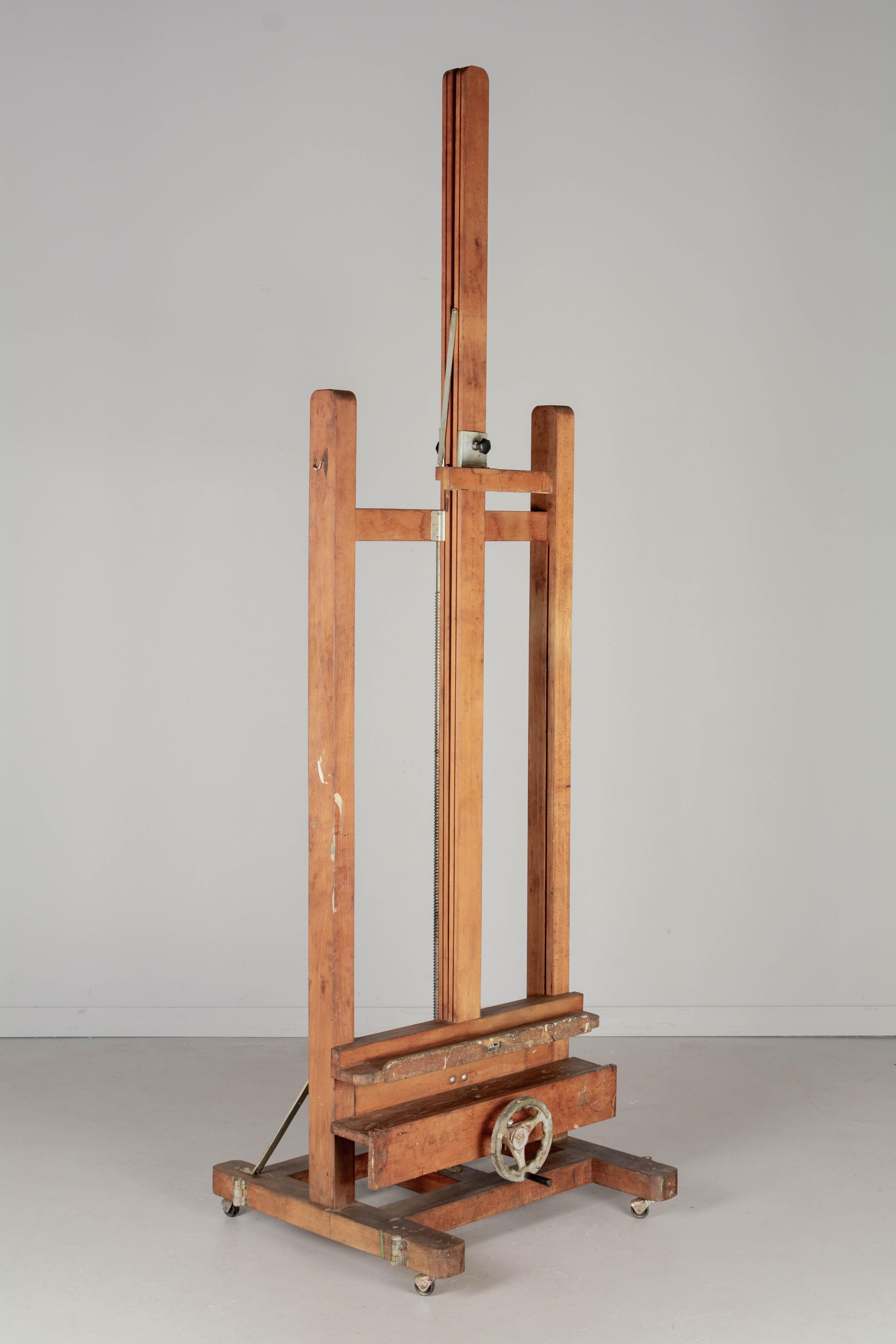 Un cavalletto d'epoca per artisti spagnoli in legno di faggio massiccio con grande morsa e meccanismo a ruota in ghisa con manovella nera. Questo cavalletto è perfetto per esporre quadri di grandi dimensioni. Una profonda sporgenza nella parte