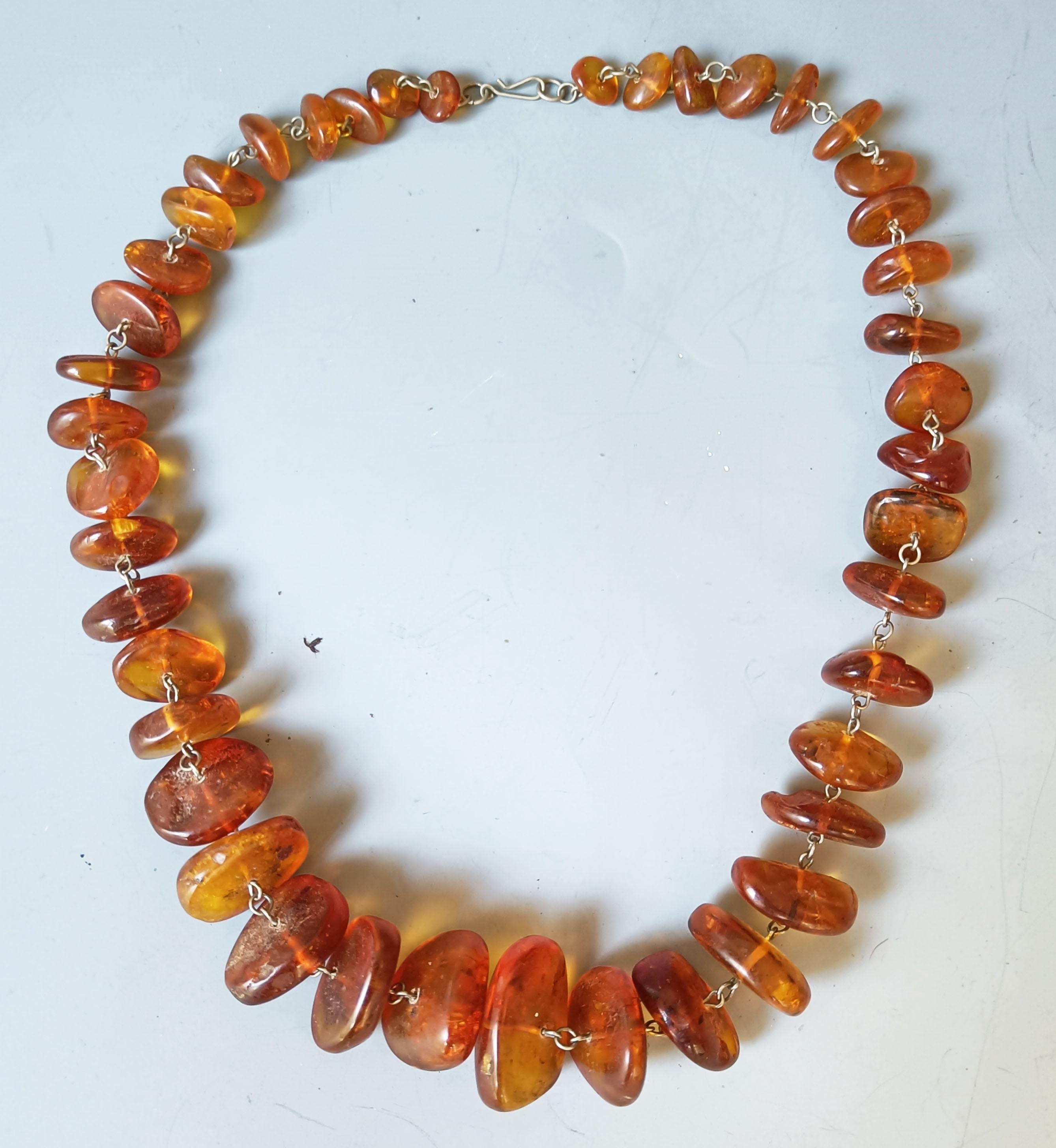  Vintage Graduated Baltic Amber Necklace 

Graduated Disc shaped Baltic amber beads strung together with  silver metal link chain
Circa 1970 s

Overall Length 70 cm bead size 1 to 3 cm   0.5 to 1.3 inches
 
 