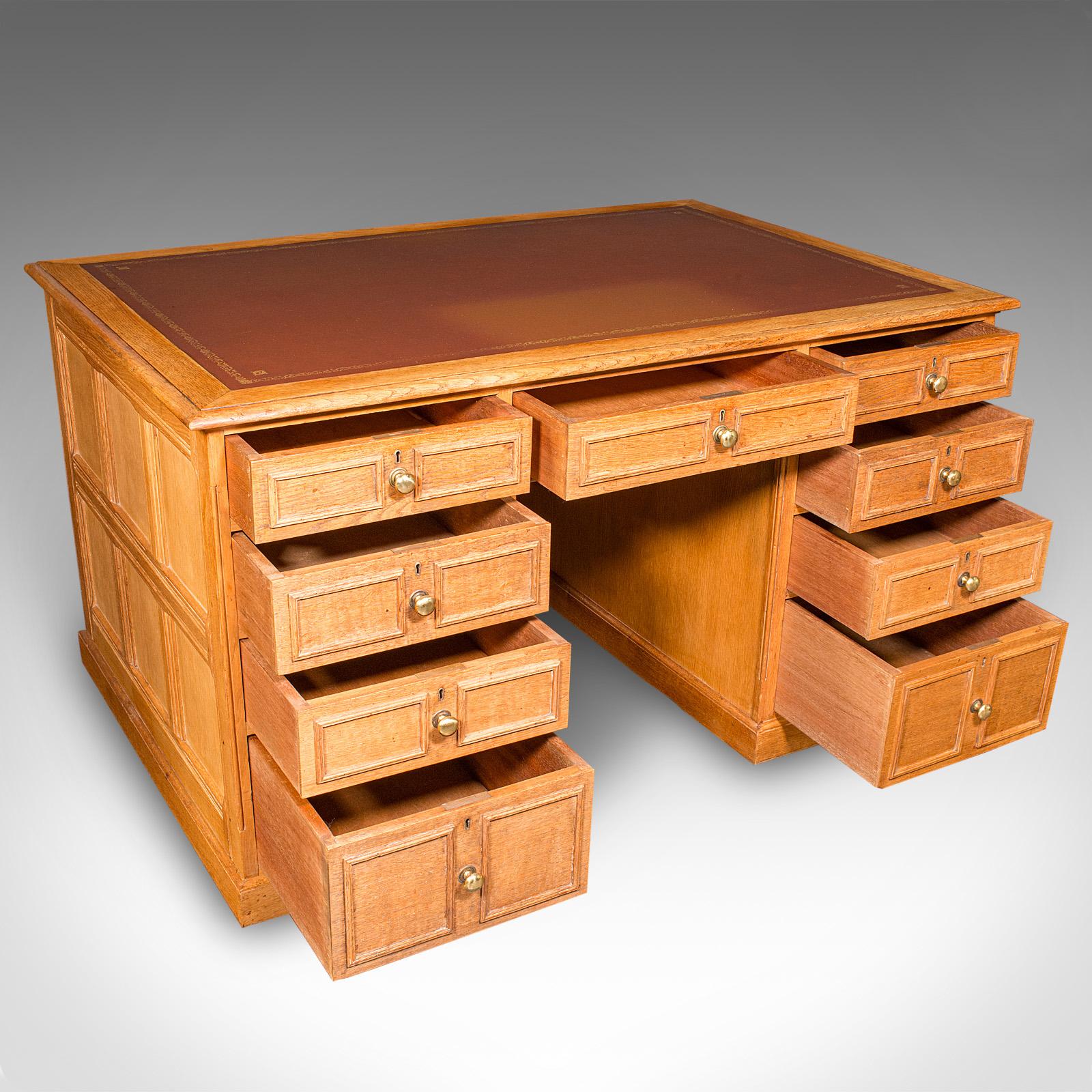 This is a large vintage kneehole desk. An English, oak panelled writing table, dating to the late 20th century, circa 1970. Crafted to a high standard, this bespoke drawing room desk offers excellent proportion, refined detail and the warmth of