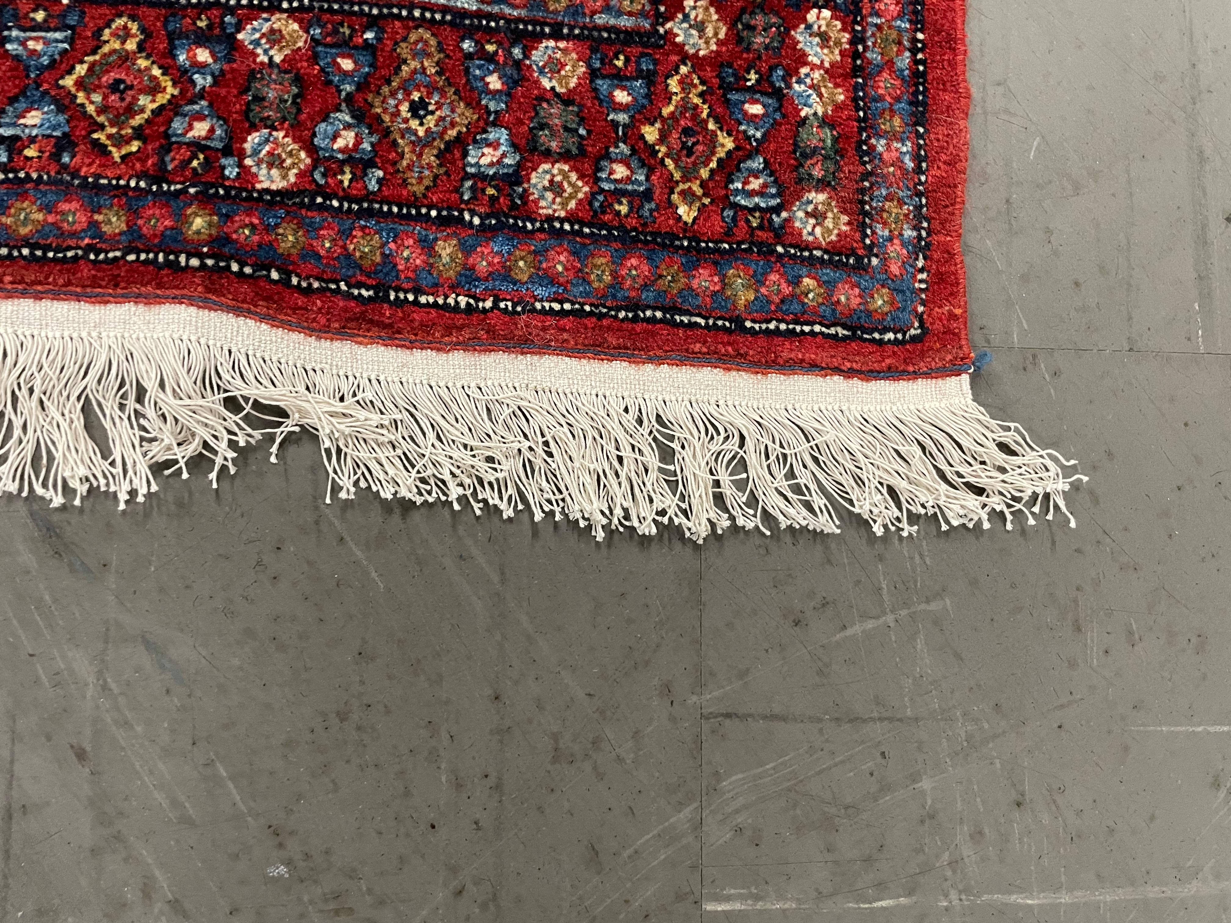 This extraordinary Persian Bidjar carpet features a bold botanical central medallion, symmetrically woven in accents of beige, red, brown, green, and cream on a deep red background. The intricate Persian Bidjar design, combined with its elegant