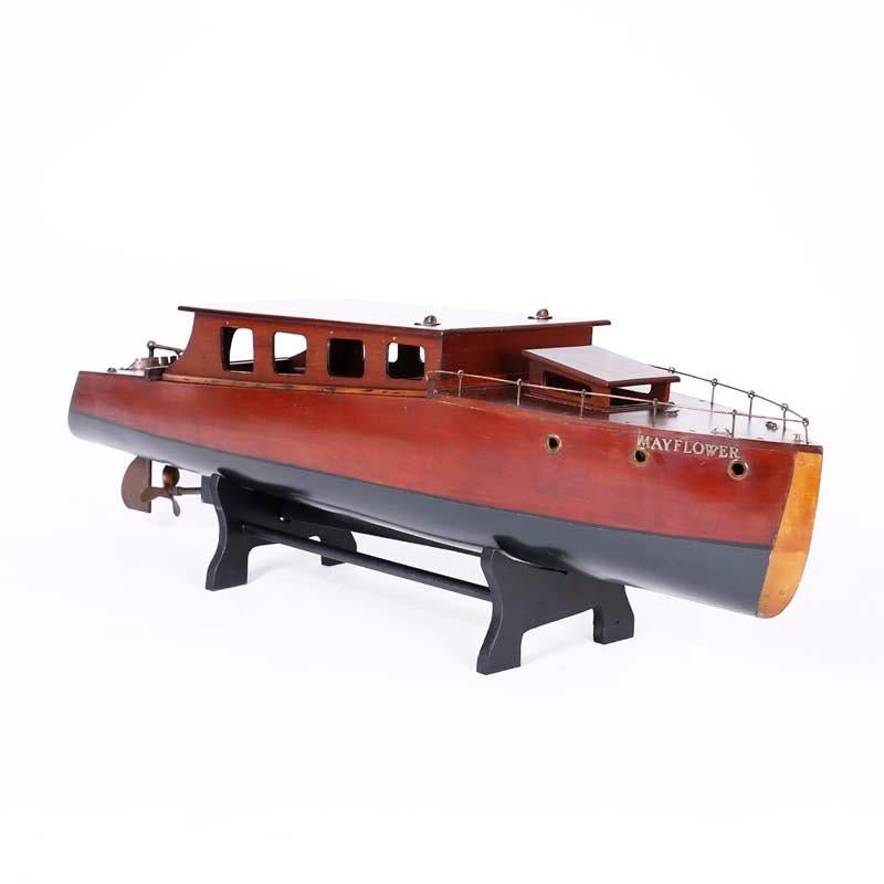 Impressive handmade boat or cruiser model, expertly crafted in mahogany with brass hardware and attention to detail, retaining her original motor and named Mayflower. Presented on a contemporary custom wood stand. The plans for this boat were