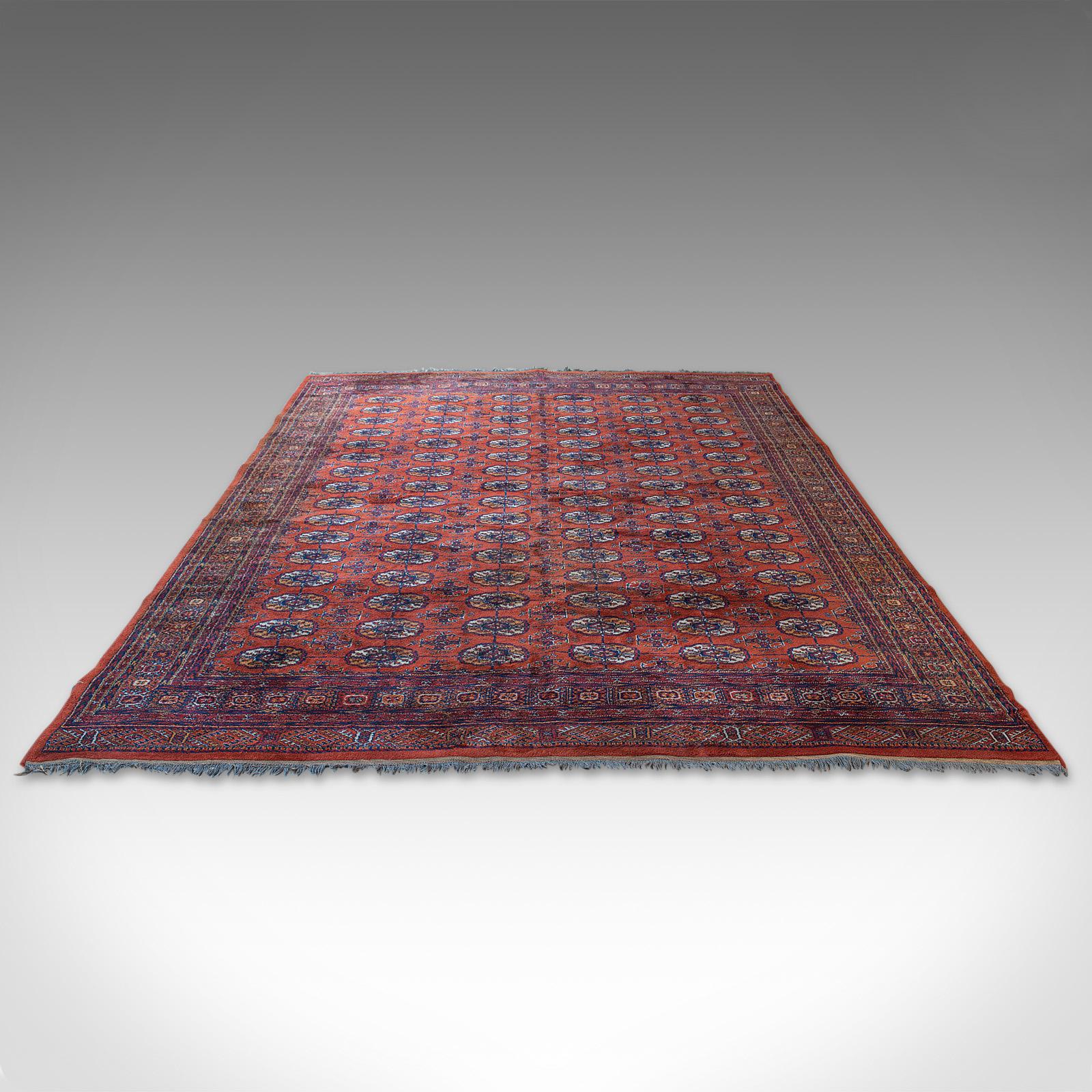 This is a large vintage Bokhara carpet. A Middle Eastern, woolen hall or living room rug, dating to the late 20th century, circa 1970.

Generously sized Qali at 341cm (134.25