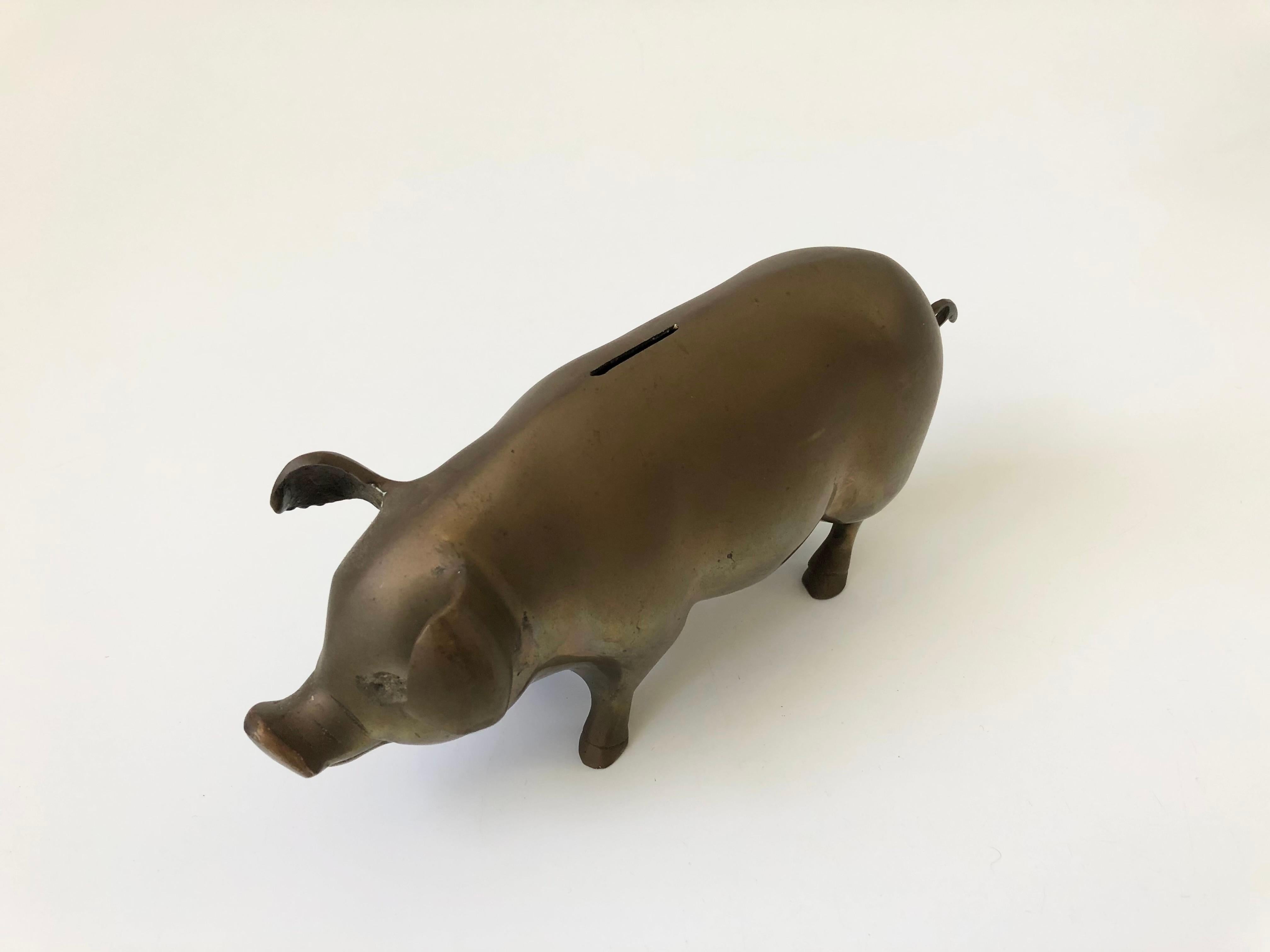 A large vintage brass pig bank. A plate on the base unscrews for removing coins.