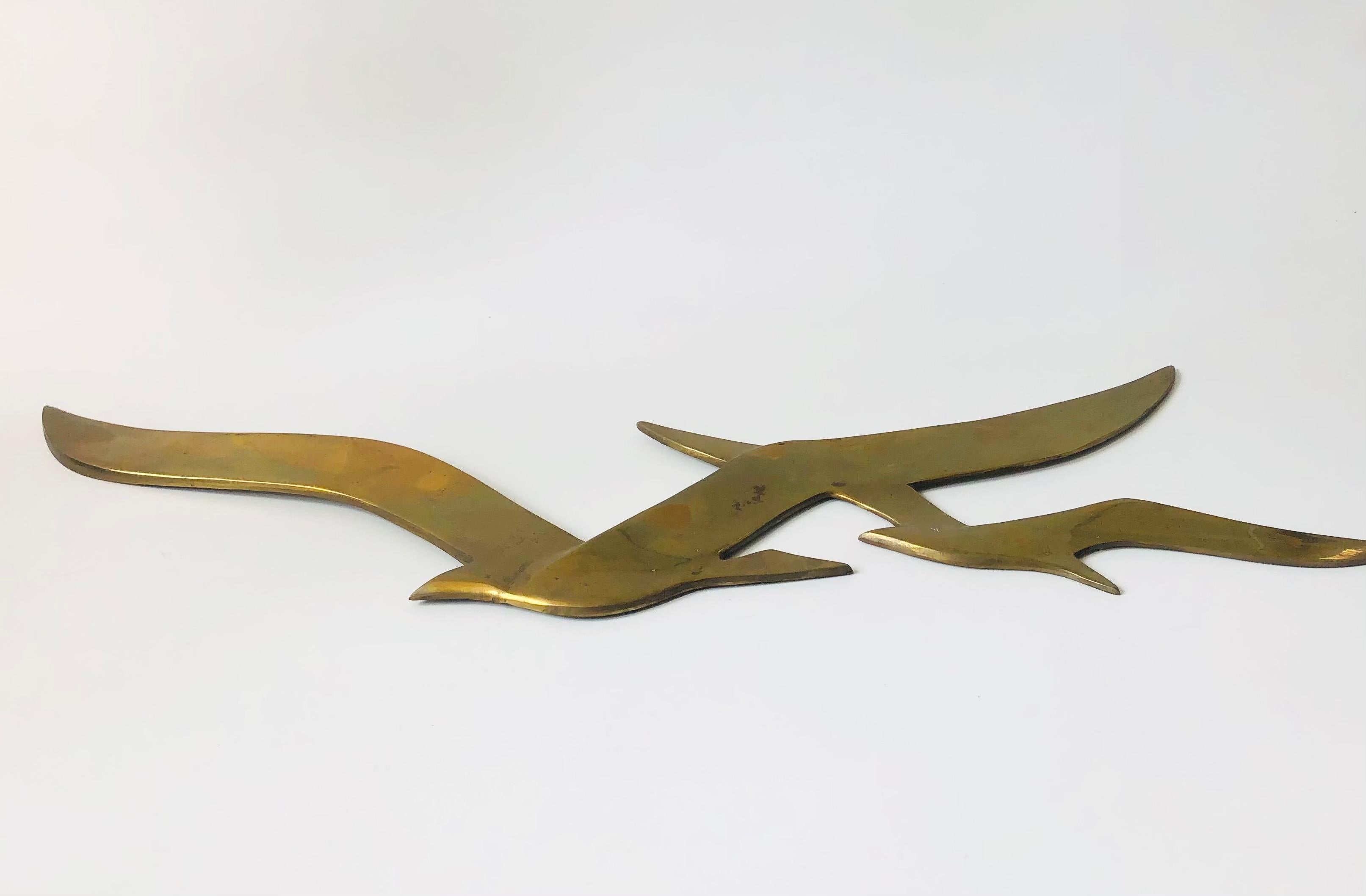 A large vintage brass wall hanging of two seagulls in flight. Ready to hang by hoops on the back.