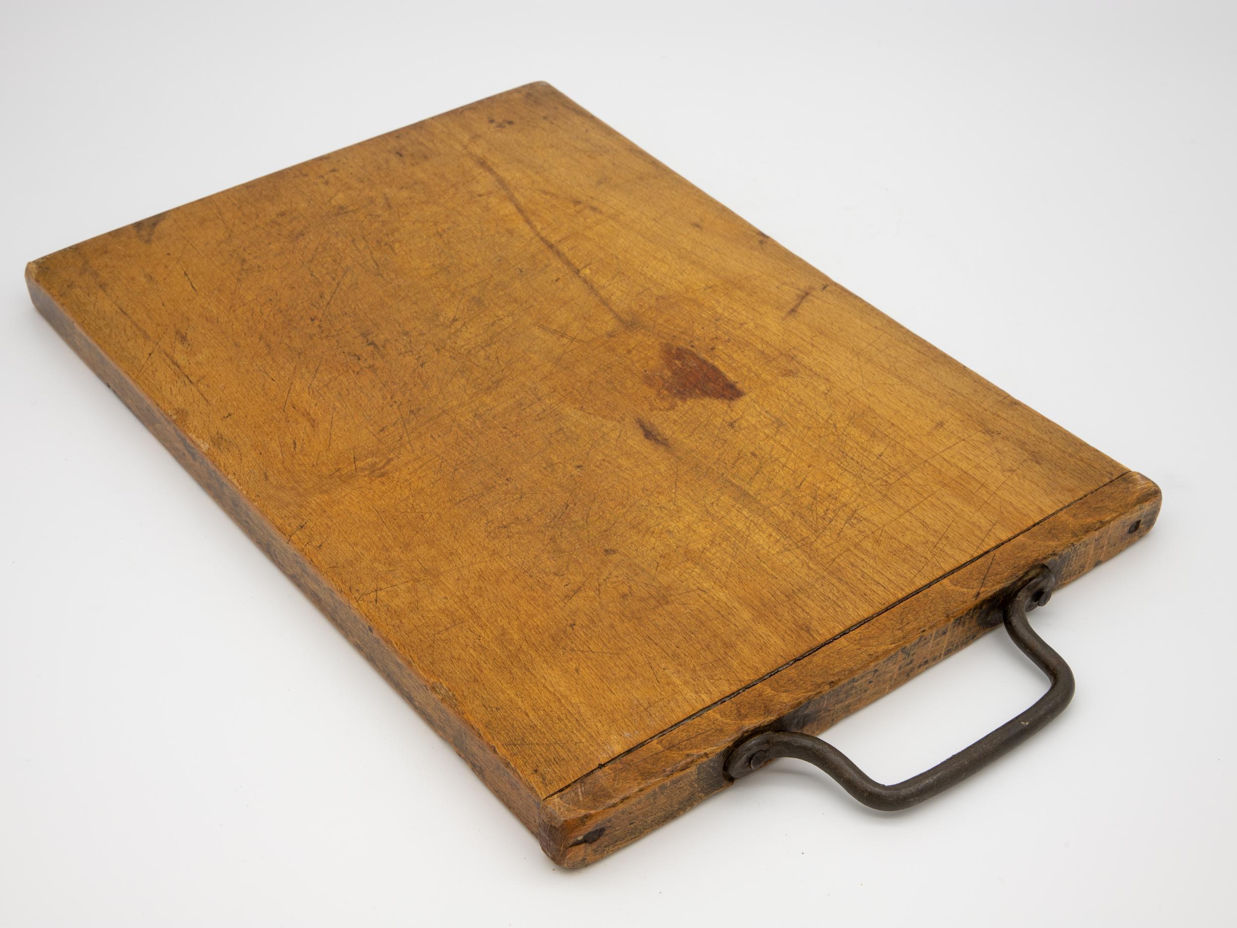 Antique chopping board with metal handle, circa 1900. Wear consistent with age and use.