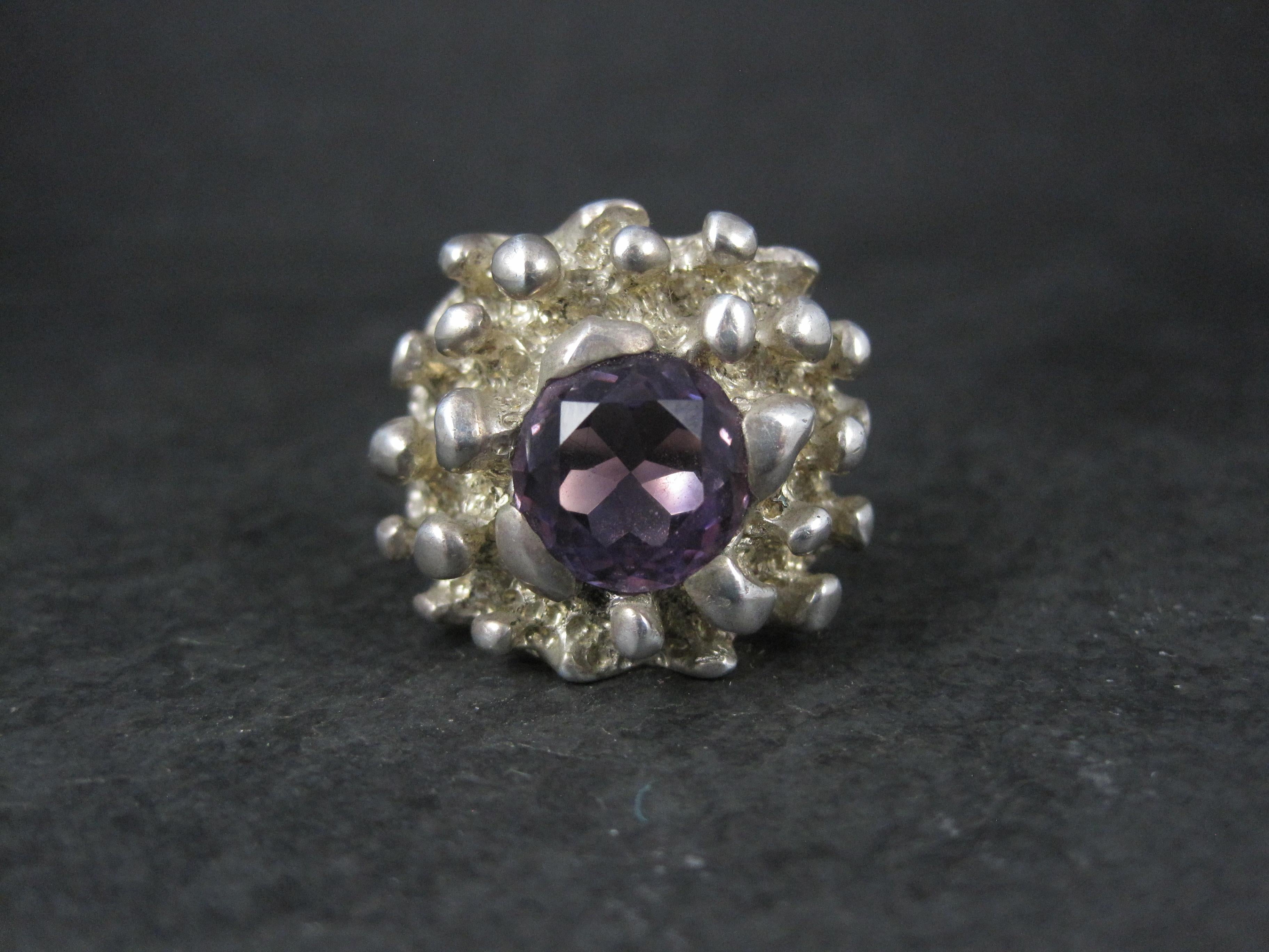 Cette magnifique bague vintage de forme libre est en argent sterling et de style brutaliste.
Elle est ornée d'une améthyste ronde de 11 mm de diamètre.

La face de cette bague mesure 15/16 de pouce du nord au sud.
Taille : 11
Poids : 24.2