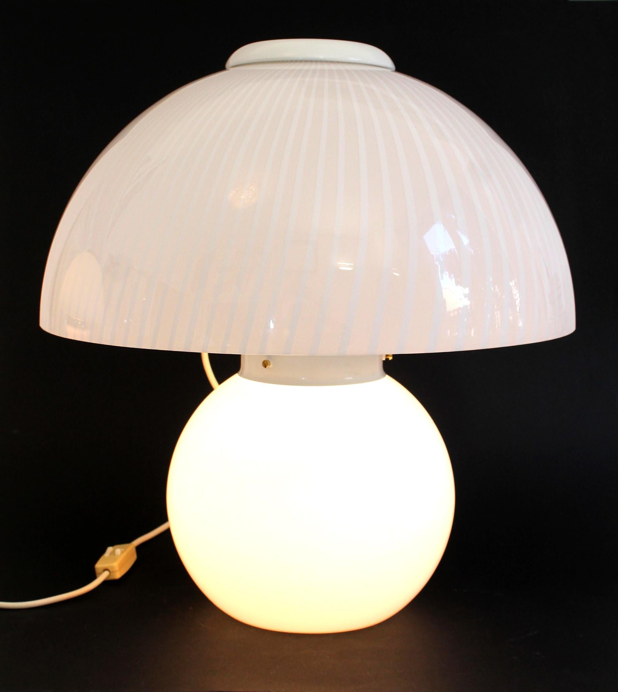 Lampe de table classique vintage en verre de Murano avec un tourbillon de champignons, fabriquée par VeLuce (Italie) dans les années 1970.

Mesures : 48 cm de hauteur x 43 cm de diamètre supérieur x 25 cm de diamètre inférieur de la base.

La