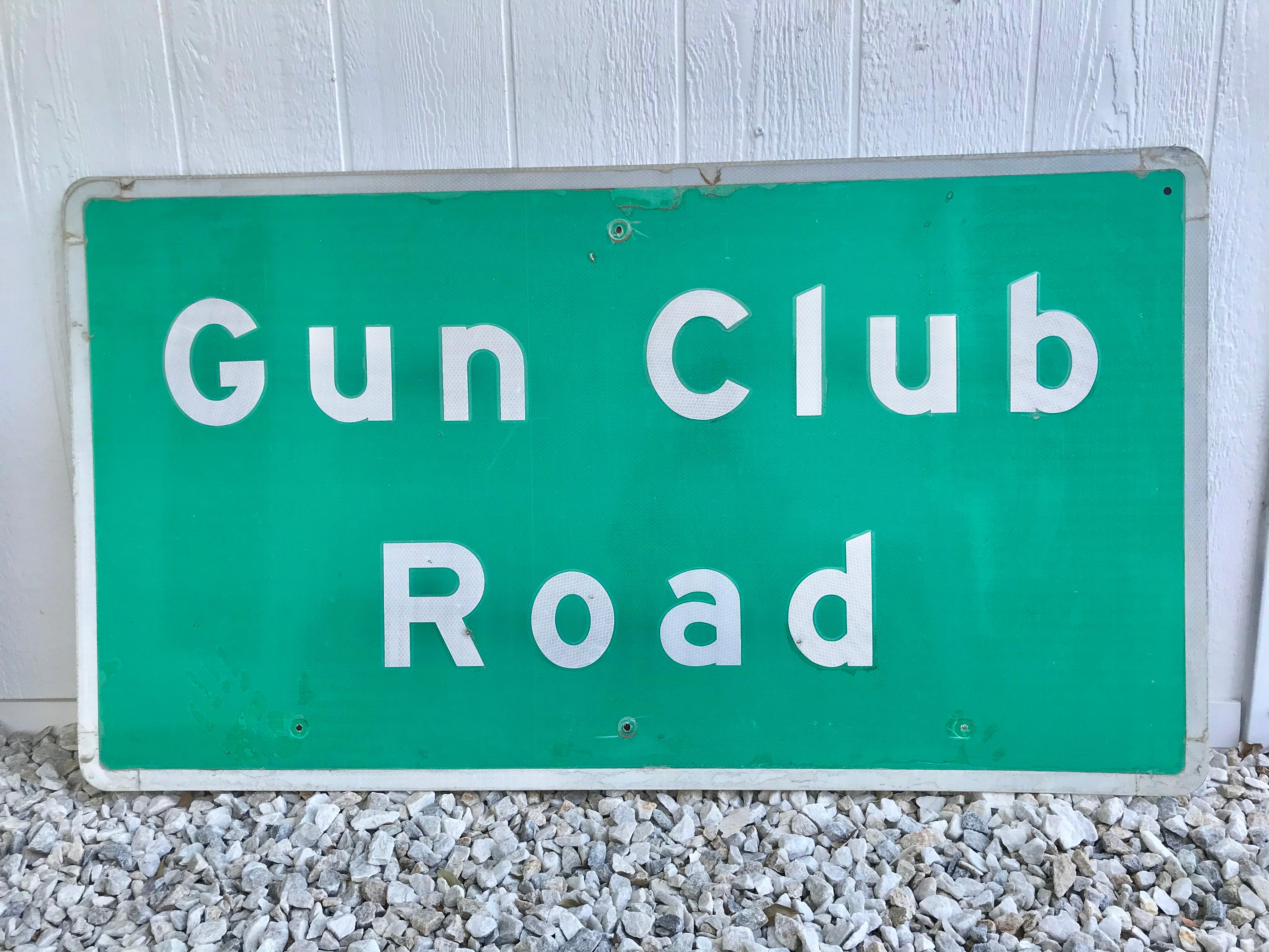 Señal de tráfico antigua de acero en la que se lee Gun Club Road. Signo se retiró en el desierto de California, al norte de Bakersfield. Letrero reflectante verde con letras y ribetes blancos. Buen estado vintage. La cubierta protectora de plástico