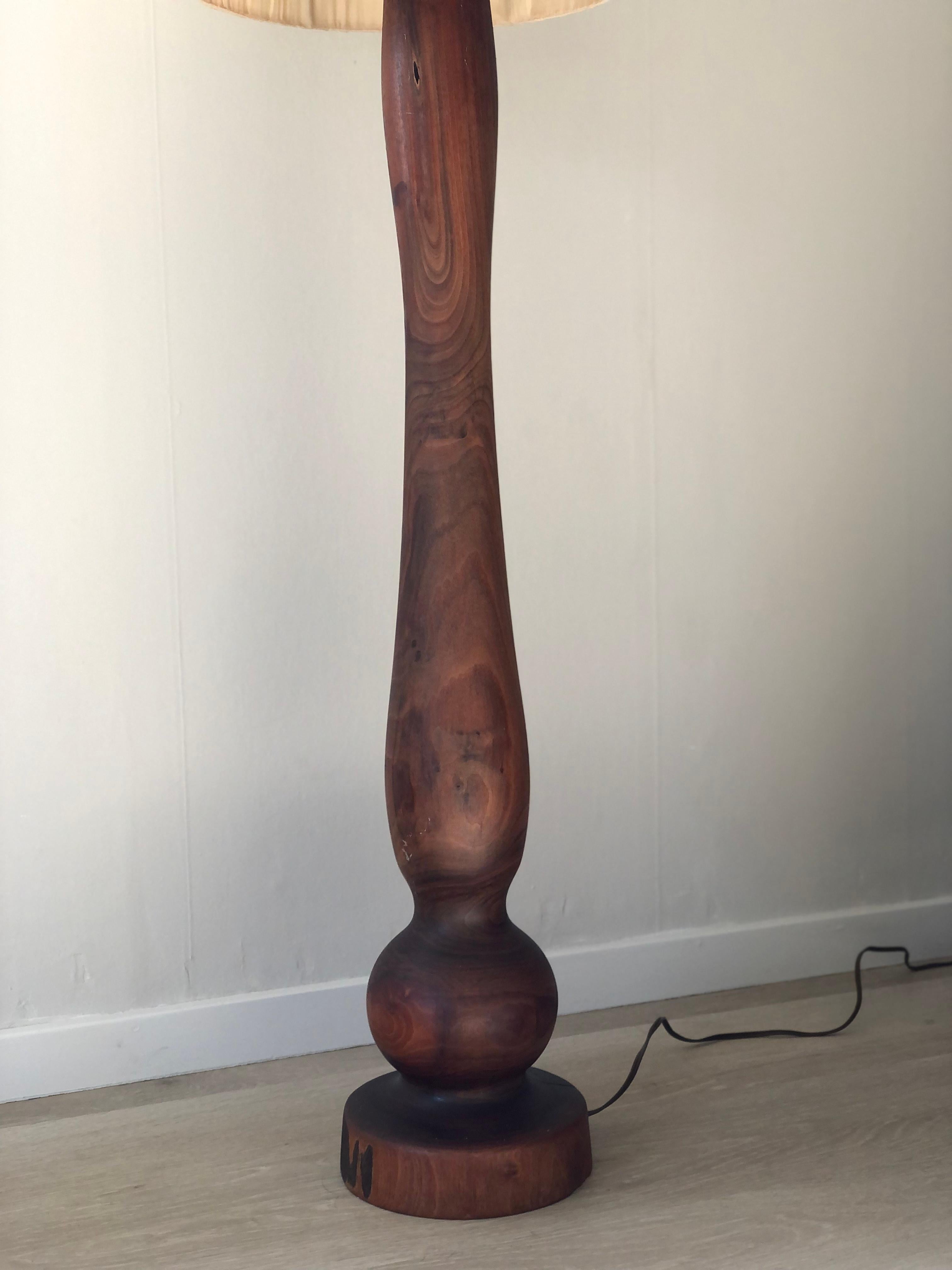 Beautiful detailed large walnut floor lamp carved from a tree trunk. The tree rings are visible. Marked ‘72 on the bottom. A cream linen corkshade on top.

Object: Floor lamp
Designer: Unknown
Style: Vintage
Marked: (unknown sign)  ‘72
Period: