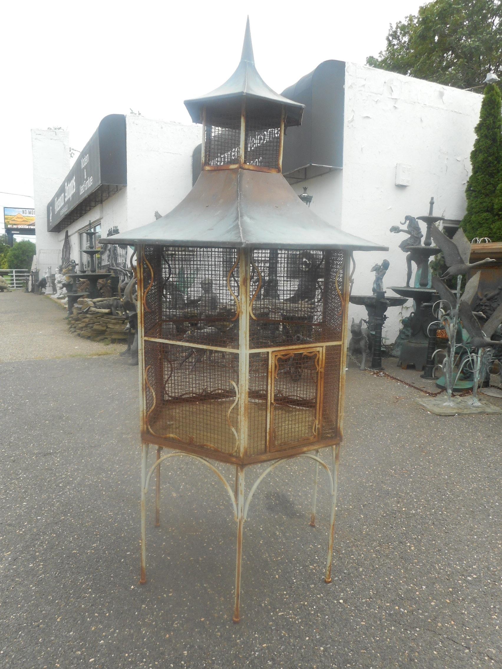 This impressive vintage cast iron bird cage stands at 101 inches tall. A two-tier octagonal design on top of a cast iron Stand with sculpted copper tops. Plenty of character with lovely curved iron detail and a unique small door on hinges. This one