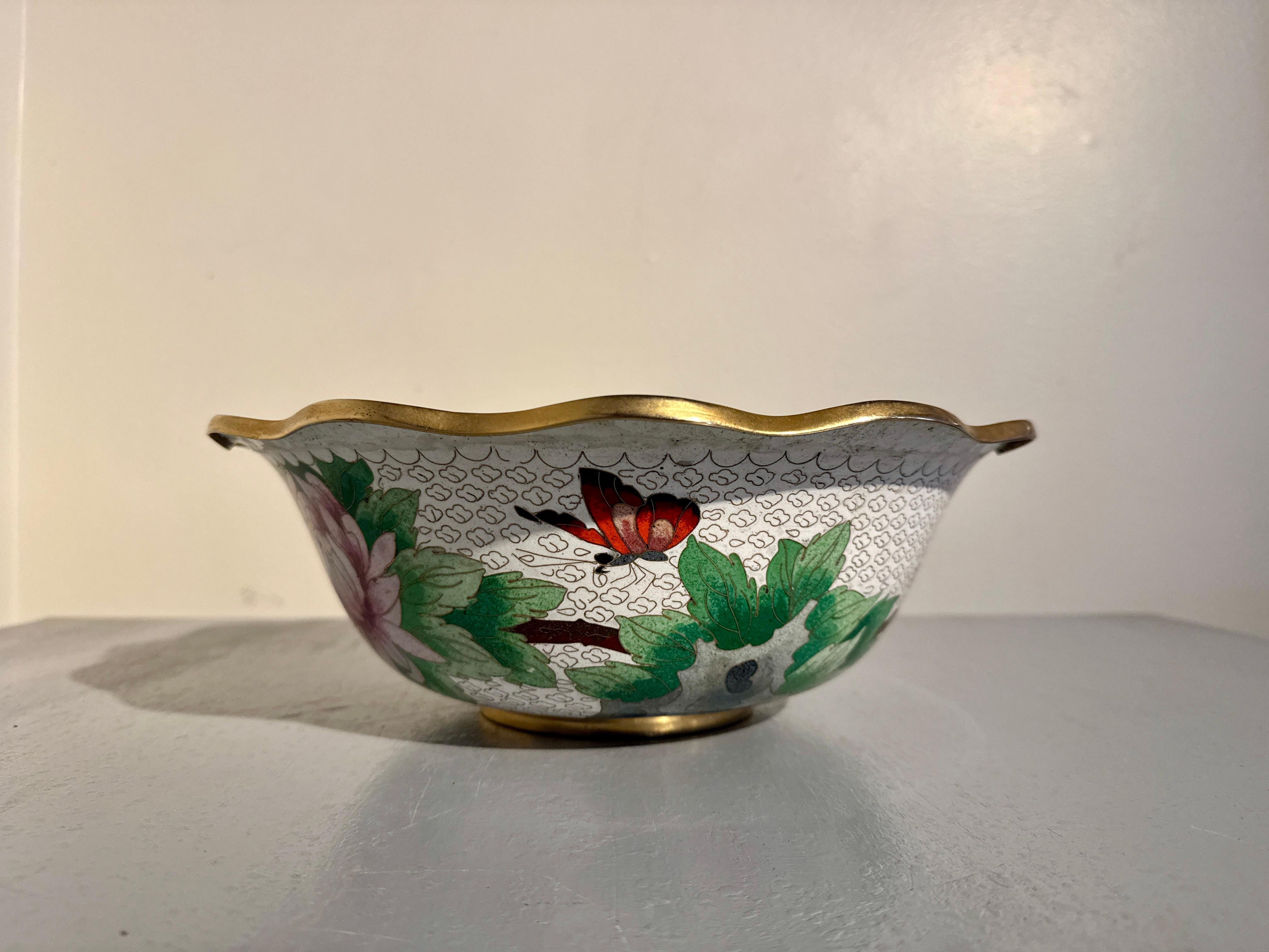 Grande e attraente ciotola d'epoca cinese in cloisonne a fondo bianco con bordo smerlato, metà del XX secolo, circa anni '50, Cina.

La grande ciotola d'epoca in cloisonne è di proporzioni generose, poggiata su un breve piede incassato, con un corpo