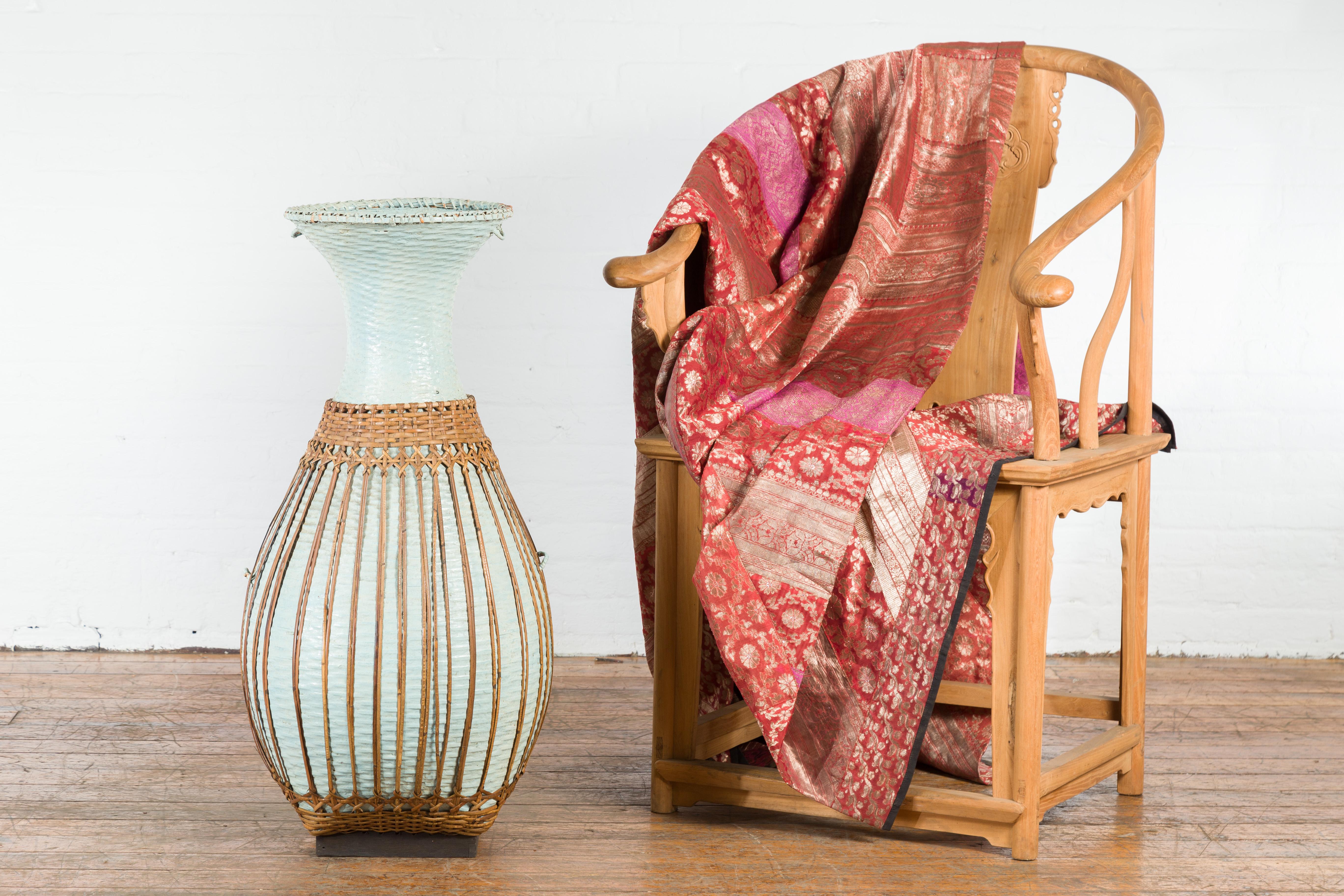 A large vintage Chinese woven rattan basket from the mid 20th century with teal color and base. Created in China during the midcentury period, this large vintage basket charms us with its vase shape and teal color. Showcasing an opening of 12