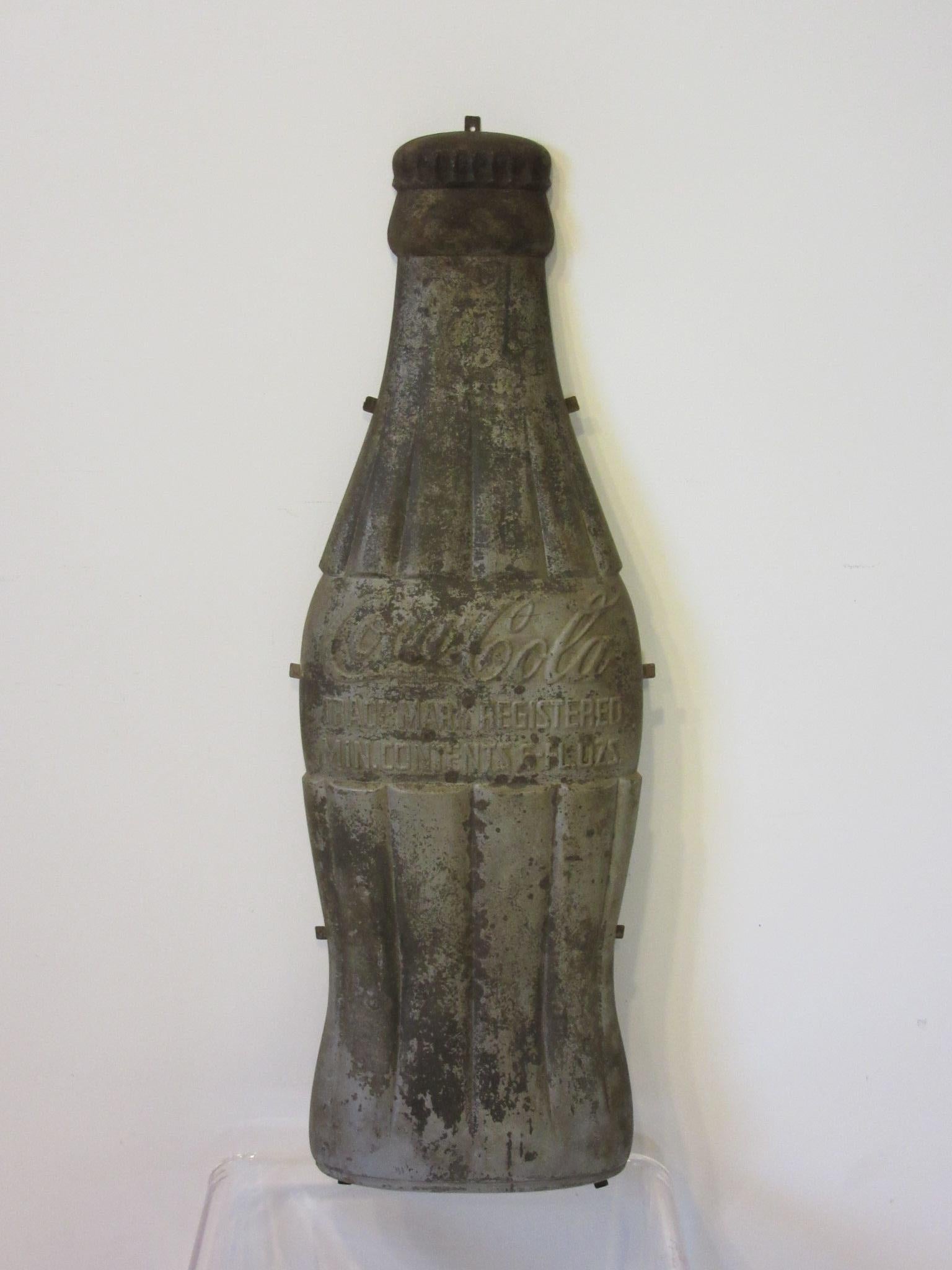 A large all embossed vintage metal Coca Cola bottle sign advertising piece having ribbed green bottle design and lettering to the front 