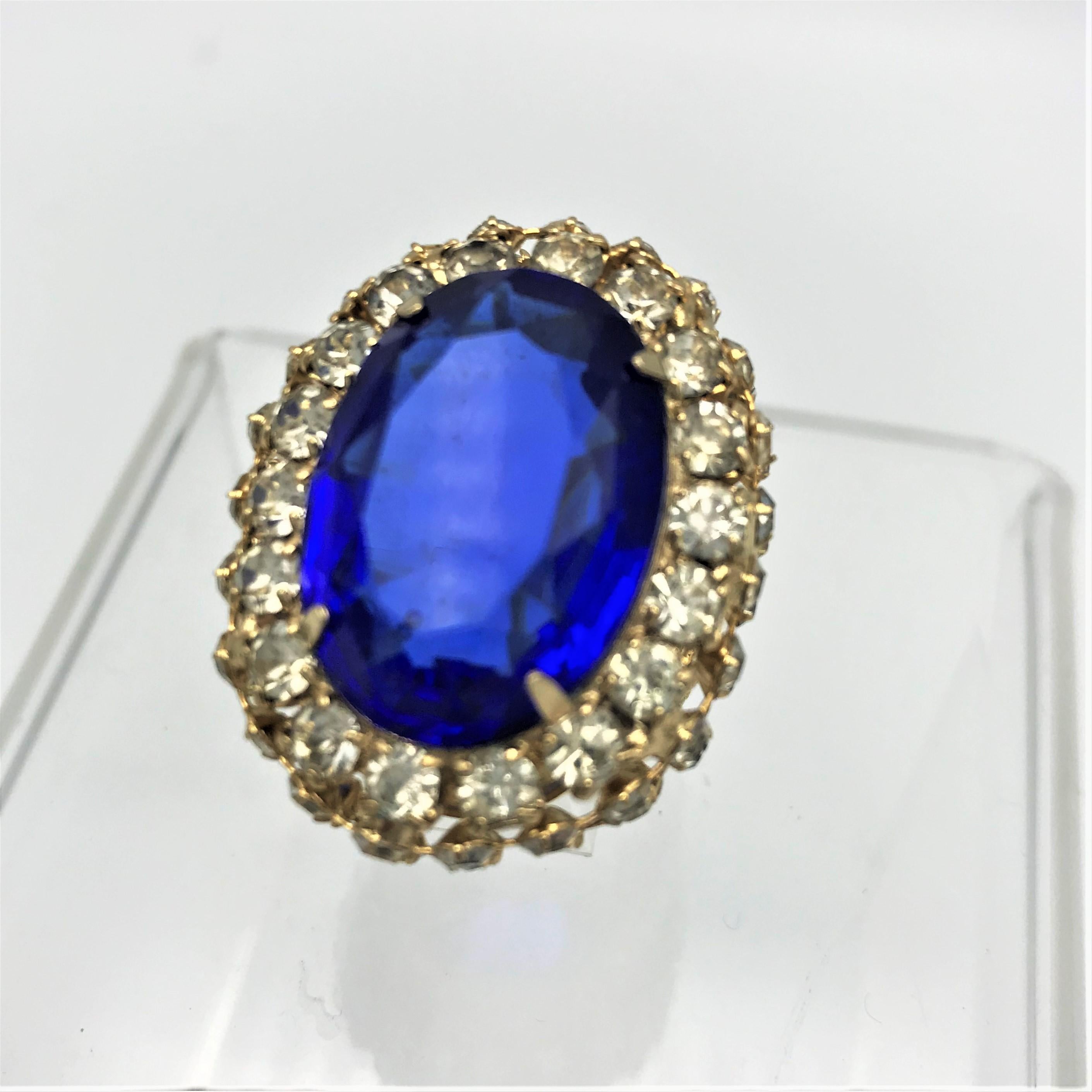 A gigantic cocktail ring with a large blue rhinestone. This is surrounded by 3 rows of clear rhinestones which are all set individually.
This ring is a piece of Hollywood history and glamor from the Harrice Miller Celebrity Collections!
Measurement:
