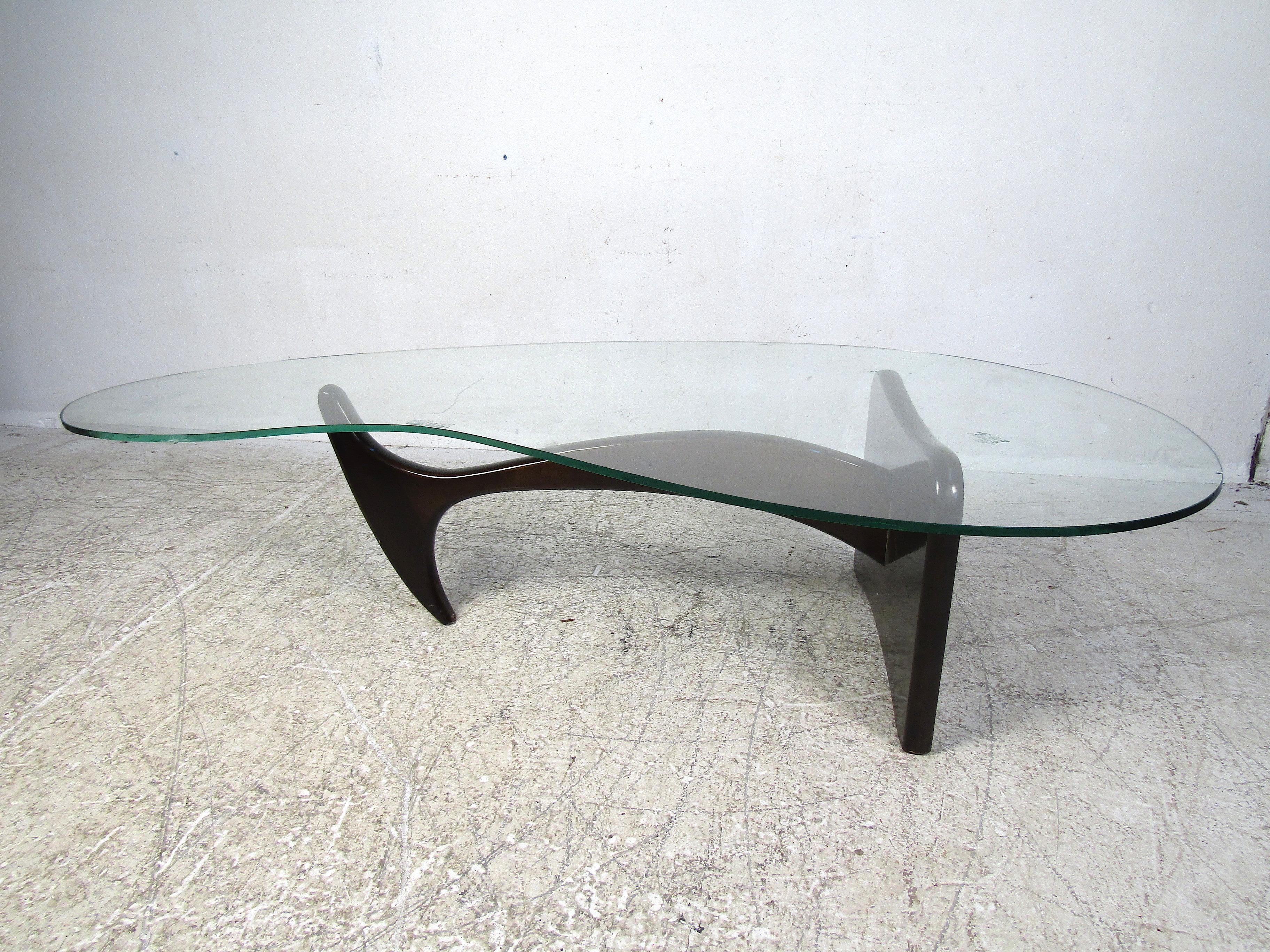Stylish vintage coffee table with a sculptural wooden base and a large kidney-shaped glass tabletop. This table is sure to prove a great centerpiece to any modern interior's living room or common area. Please confirm the item's location with the