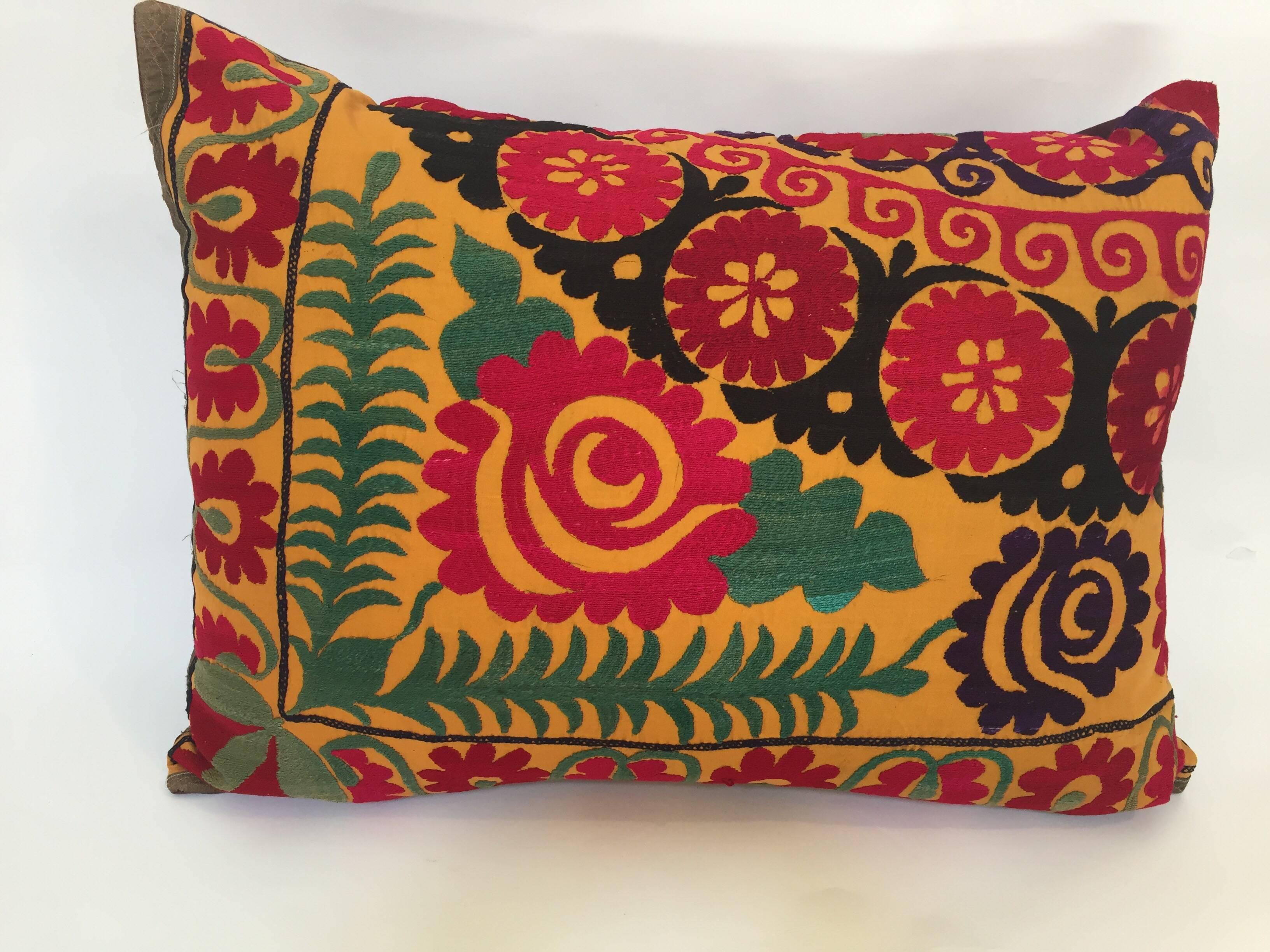 Large vintage colorful Suzani embroidery lumbar pillow red with colorful threads. 
A reddish embroidered pillow with flower motifs in shades of black, red, yellow, white, green, magenta, with linen backing and zipper in the back. 
The pillow is made